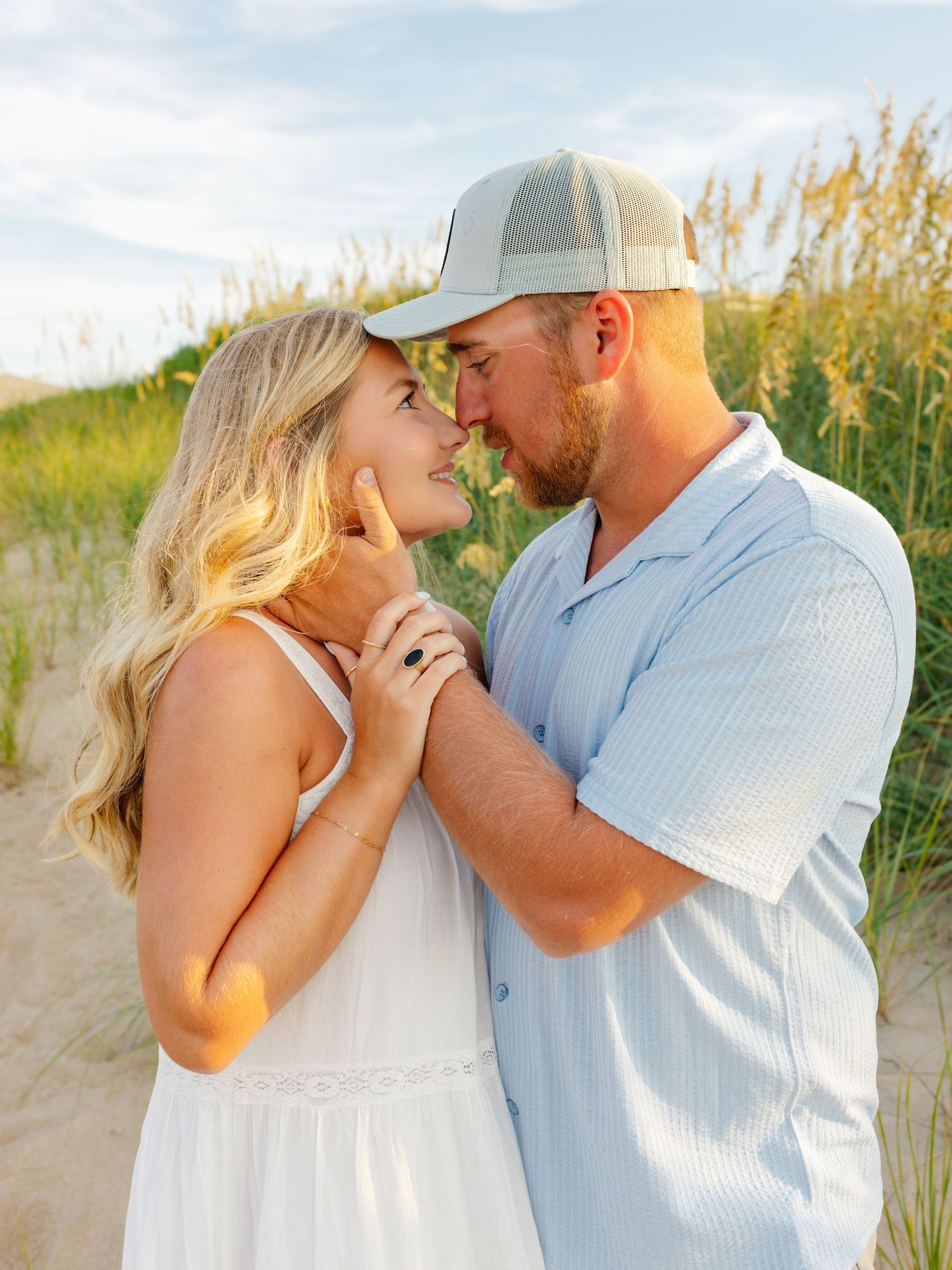 Intimate couple portrait session in soft lighting among beach dunes at sunset.