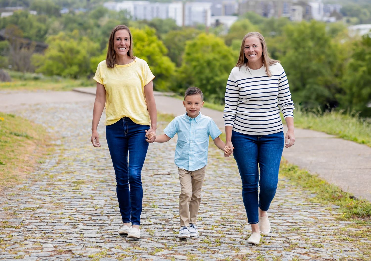 Family members in coordinated outfits walk together on a scenic outdoor path during a sunny day.