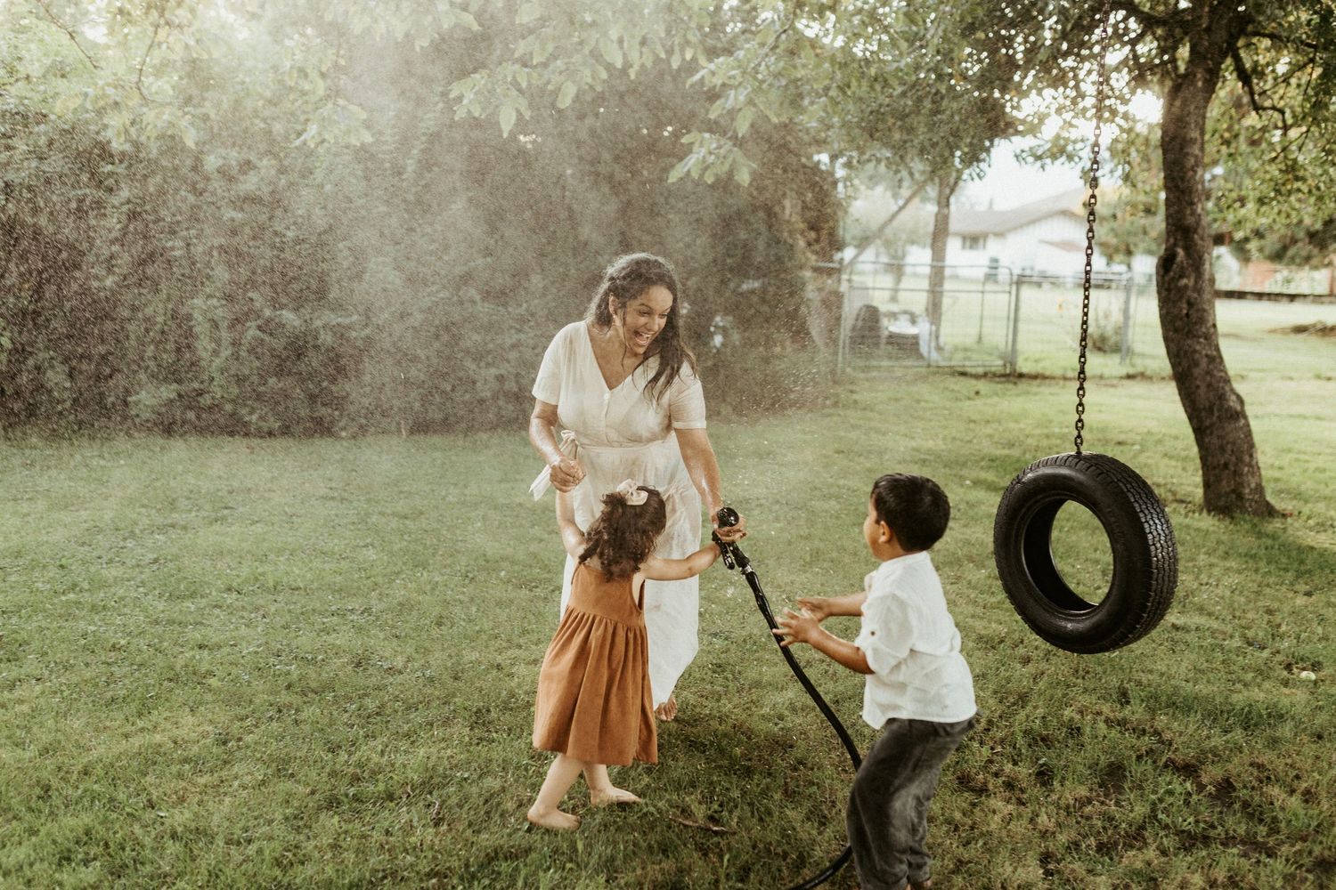 Children playing on a tire swing in a sunlit outdoor setting.