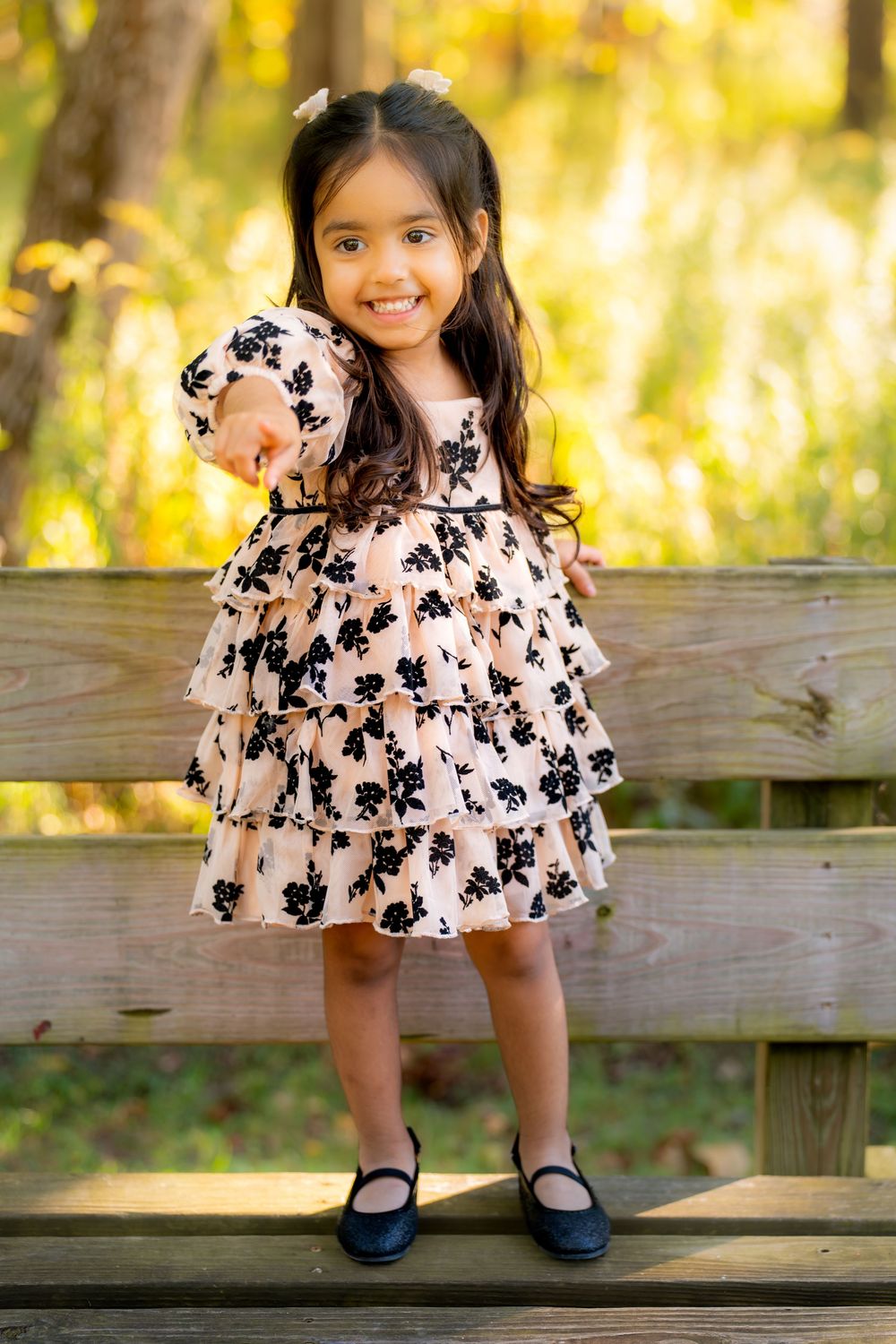 A floral print dress and black shoes are shown in a series of photos on a wooden bench in golden sunlight.