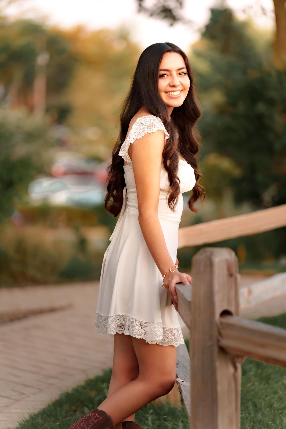 A white lace dress is featured in outdoor portrait photos along a wooden fence.
