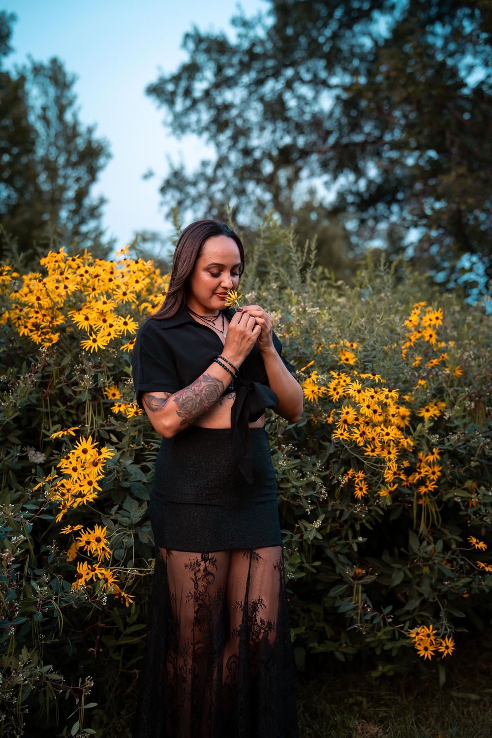 A black outfit contrasts beautifully with bright yellow flowers in an outdoor setting.