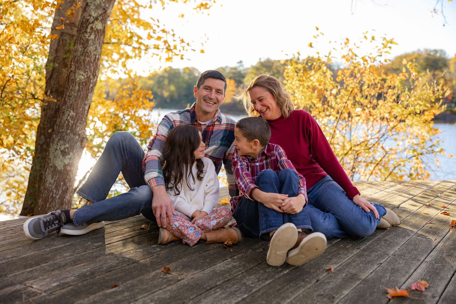 Family enjoying autumn colors while sitting together on fallen logs in a scenic forest setting.