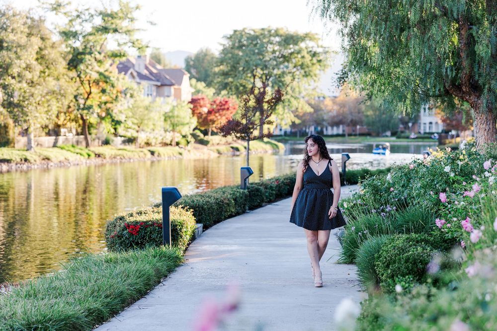 A peaceful path along a lake with trees and greenery in the background.