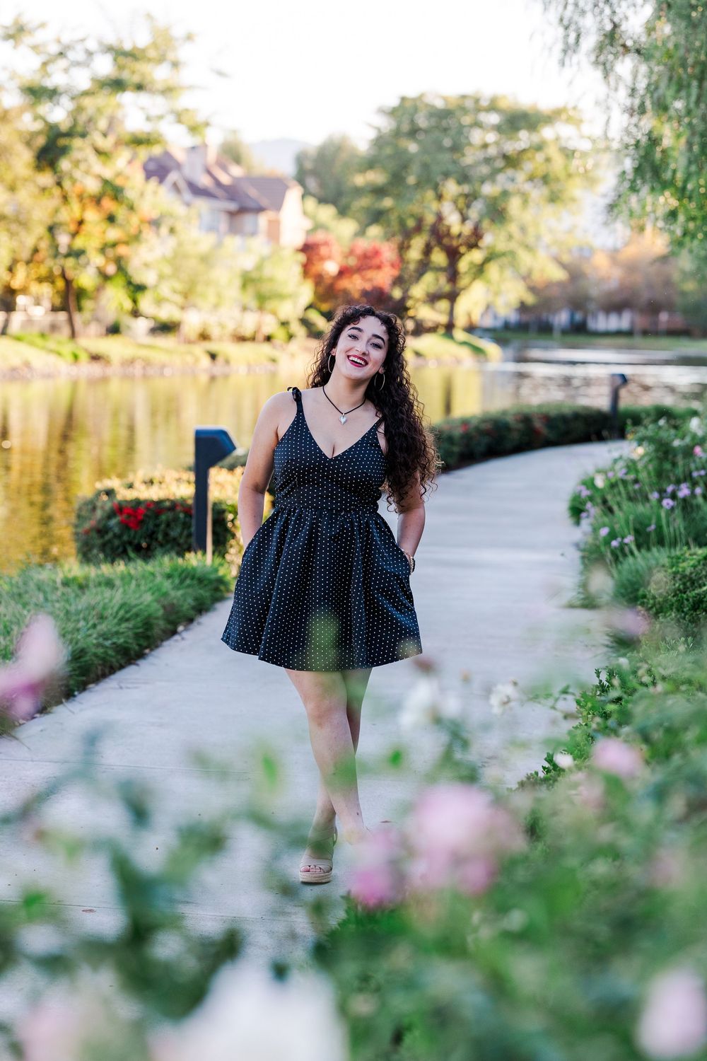A polka dot dress twirls in a garden path during golden hour as flowers bloom in the foreground.