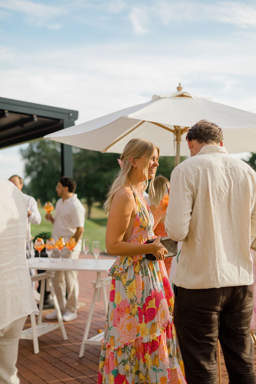 Diners enjoy wine and conversation at a restaurant's covered outdoor patio with checkered tablecloths.