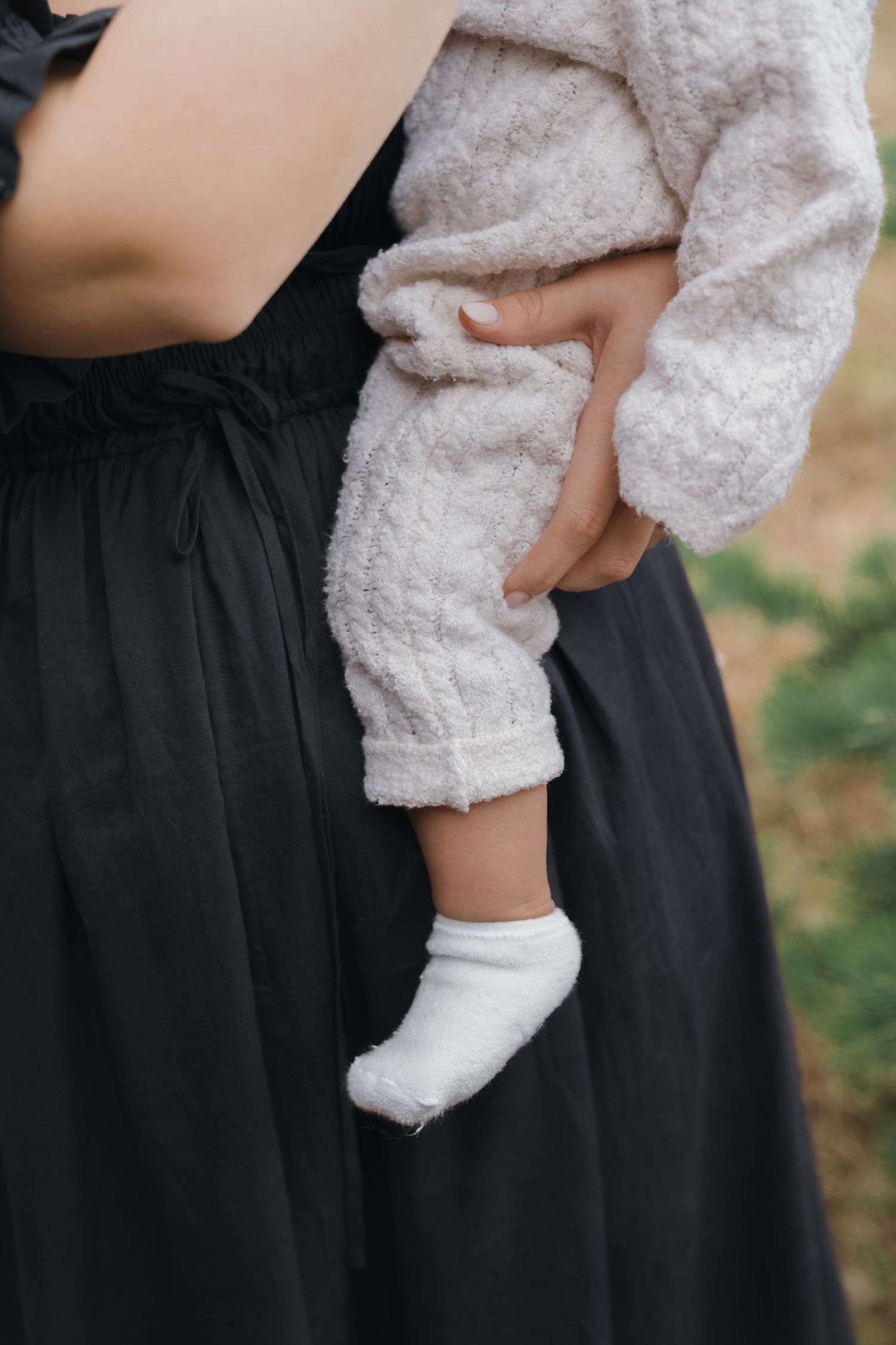 Close-up view of a person wearing a fluffy white sweater and black skirt against a blurred background.
