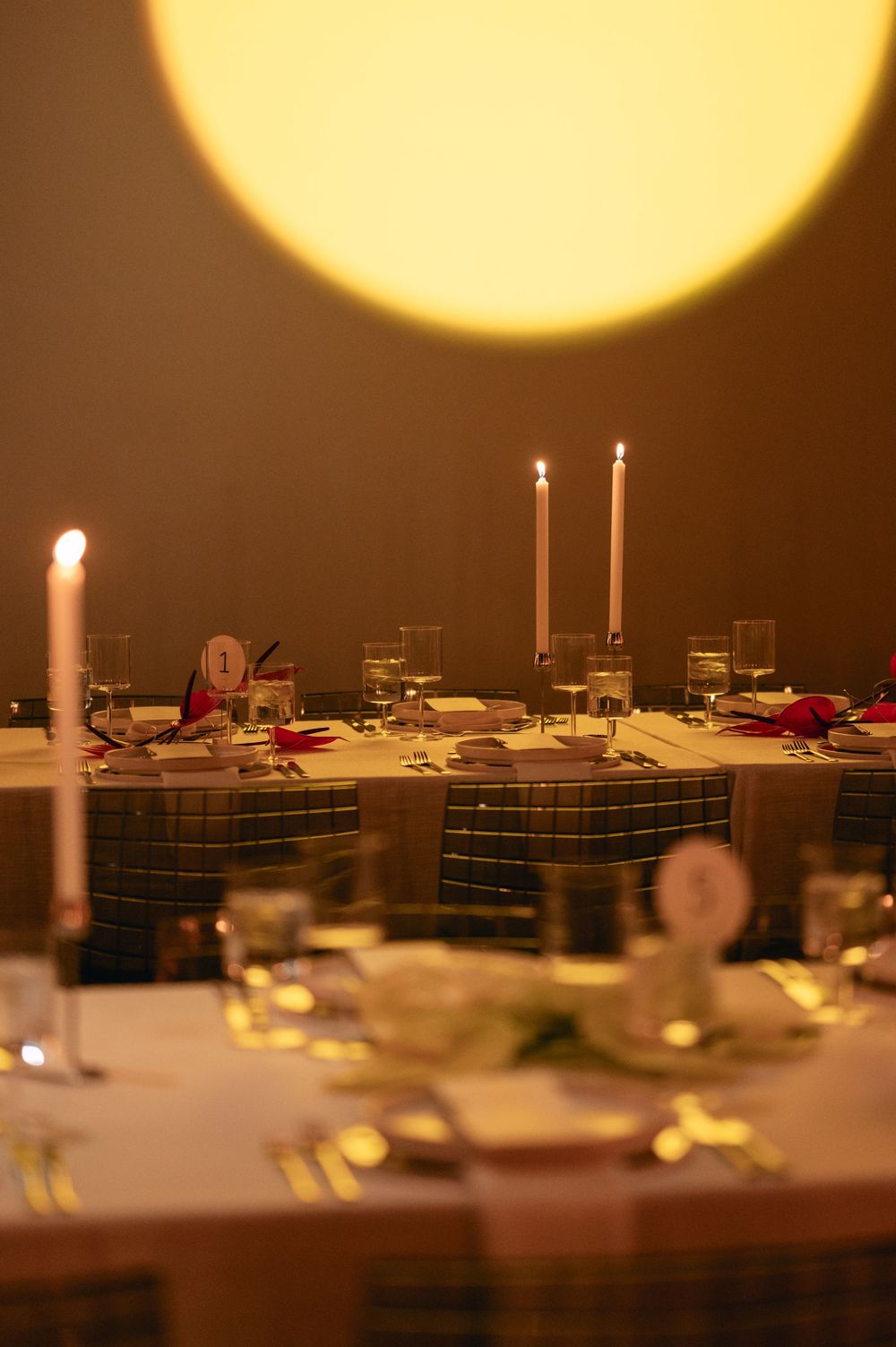 Candlelit dining tables set with elegant place settings and glowing taper candles create a romantic ambiance.