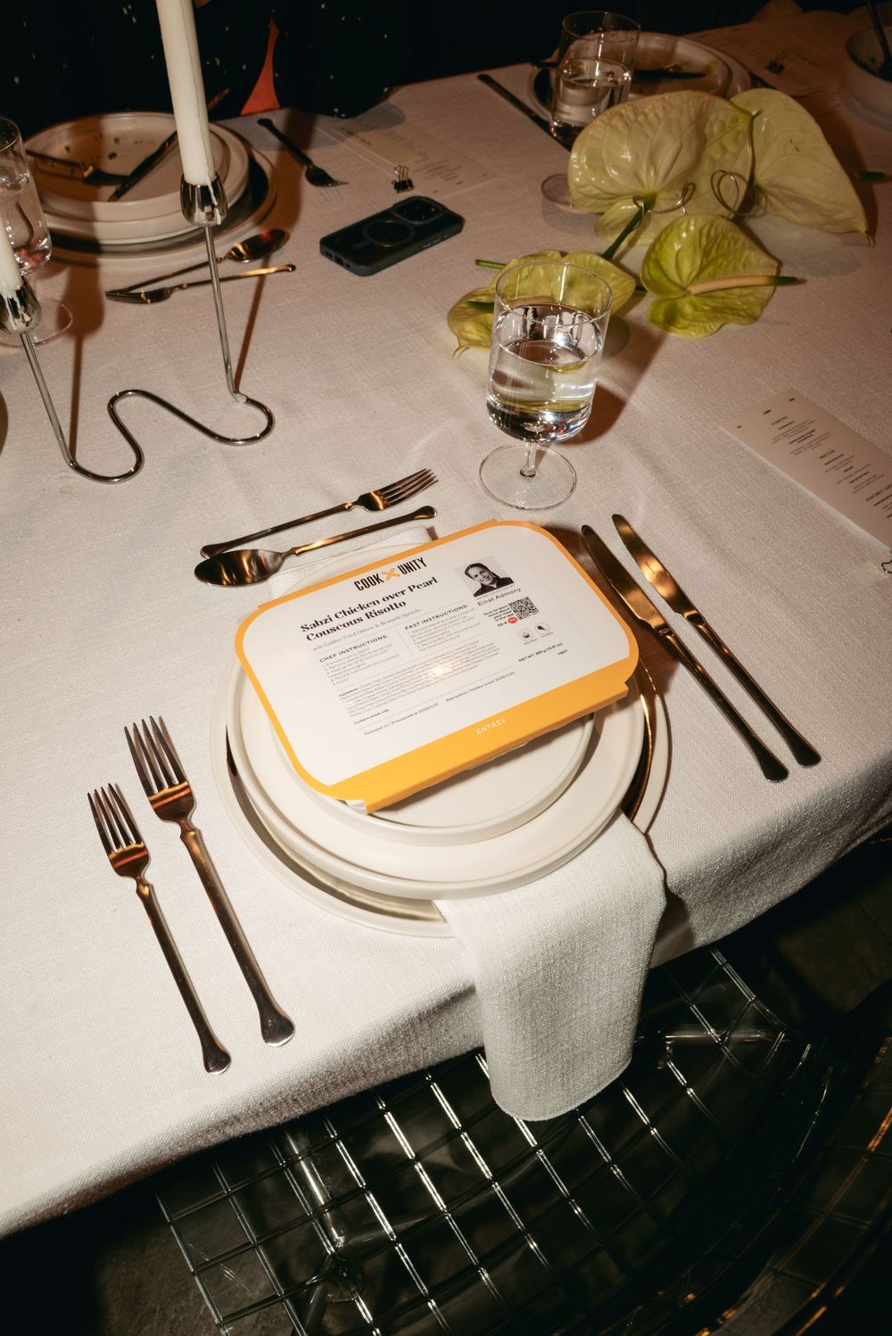Elegant table setting with white tablecloth, cutlery, menu card, candle and glassware at a fine dining restaurant.