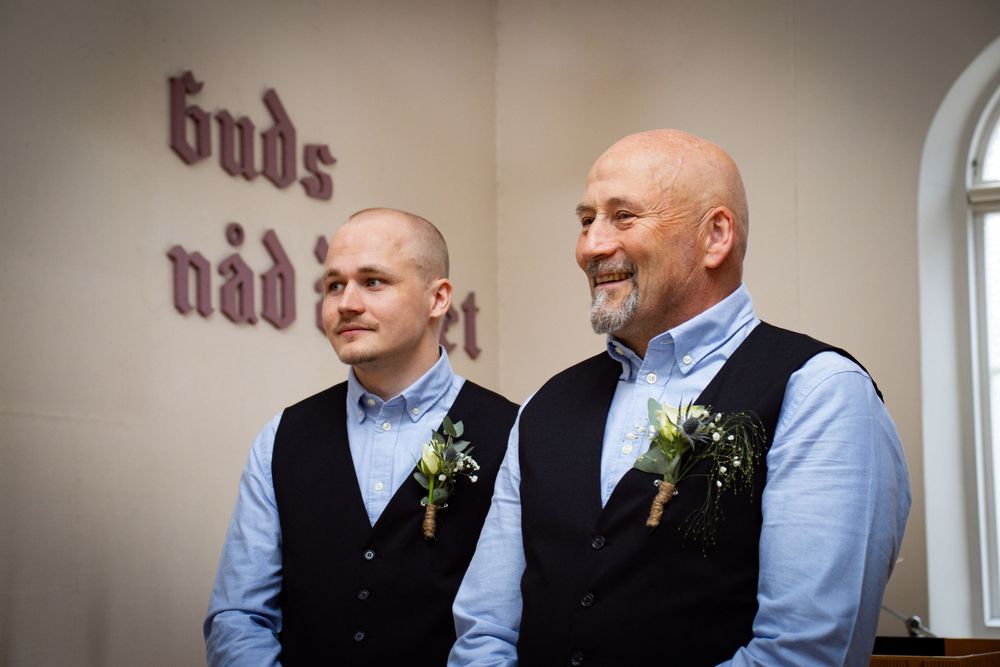 To brudgommer foran vegg med tekst, borgerlig bryllupsseremoni fotografert av Prospectxmedia.