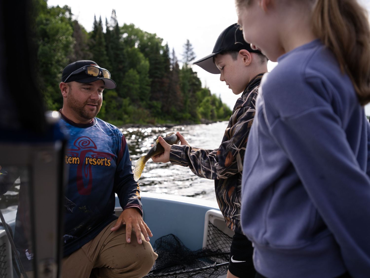 Anglers gathered around a boat discussing fishing techniques on a sunny day.