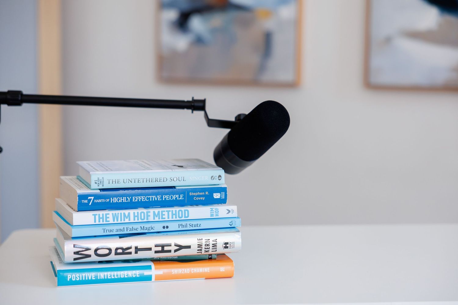 Stack of blue and white books with a black microphone on a light gray surface.