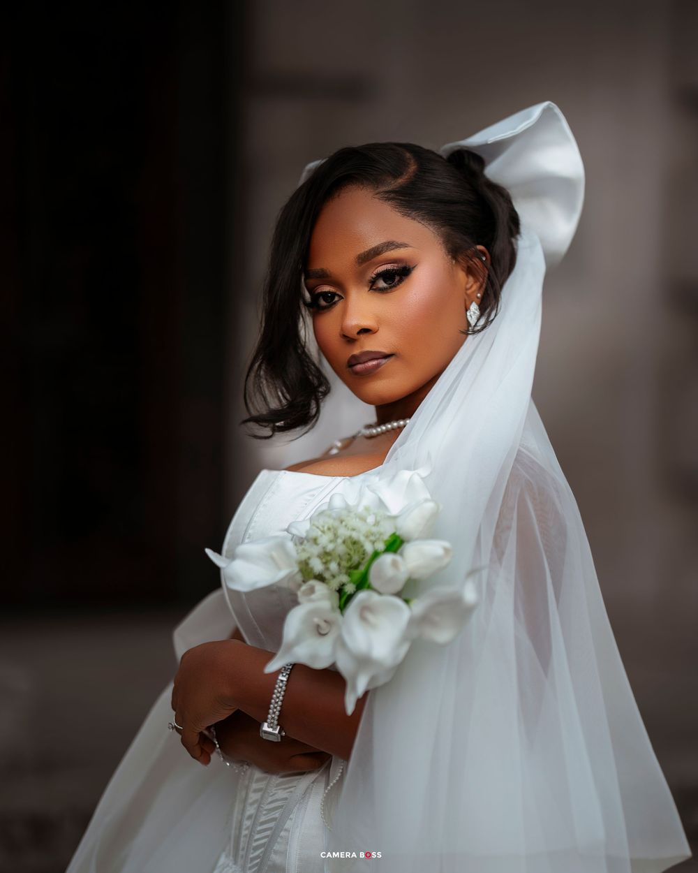 Elegant bridal portraits showcasing a white wedding gown and flowing veil against a dark background.