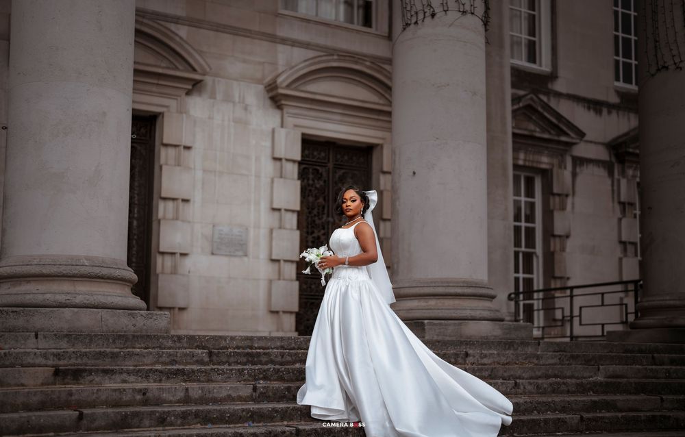 Bride in flowing white dress twirls gracefully on stone steps of historic building during wedding photoshoot.