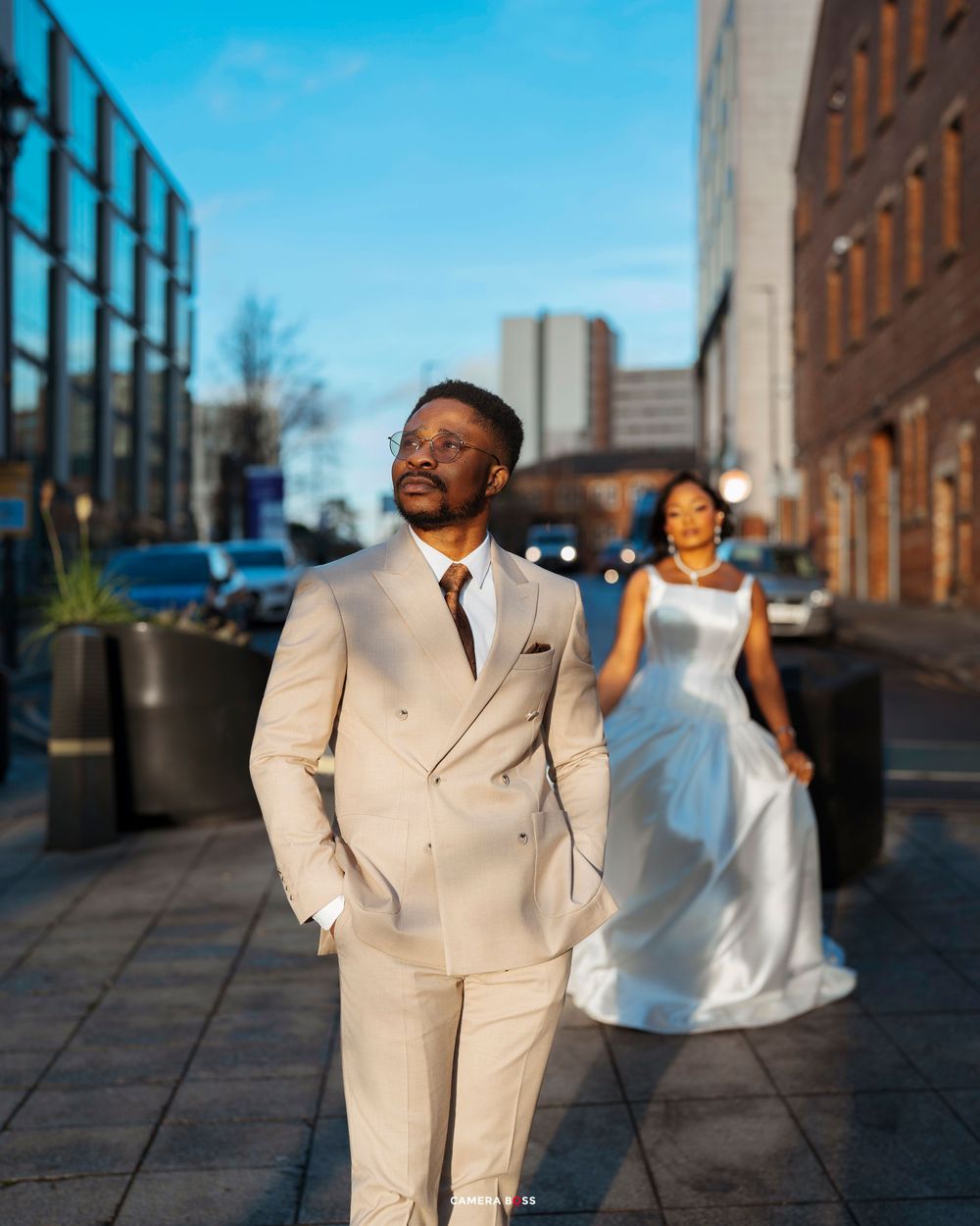 A joyful couple in formal attire dances together on a city rooftop during sunset.