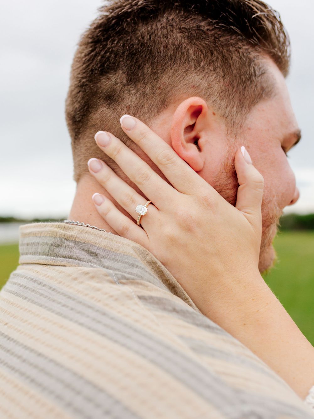 Close-up shot showing hands gently caressing a neck against a cloudy sky background.