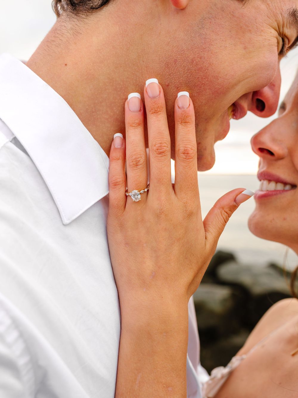 Detail shot of hands displaying new engagement ring during beach proposal.