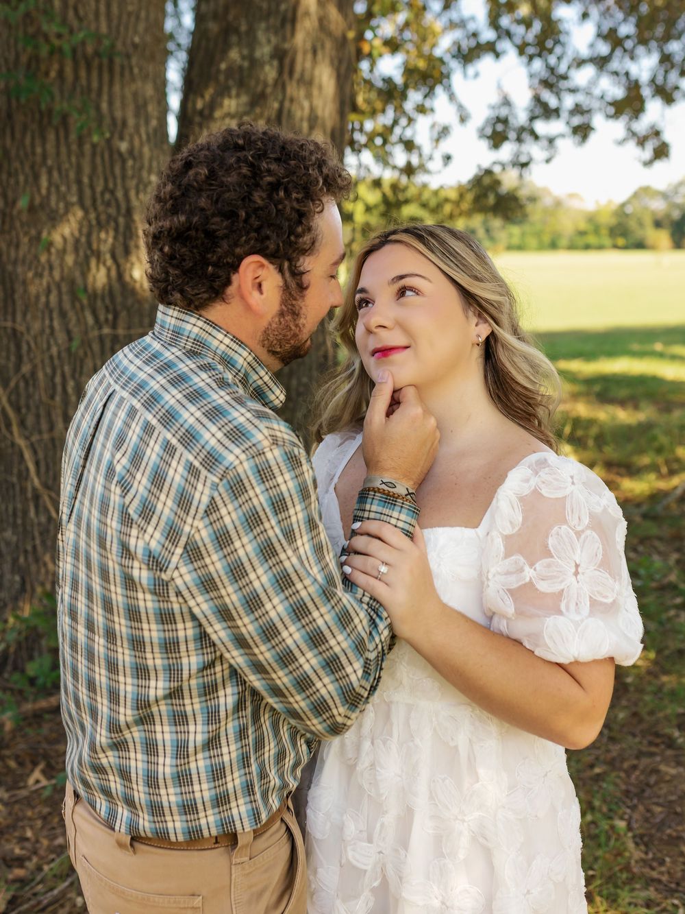 Romantic outdoor portrait session with couple in white lace dress and plaid shirt.