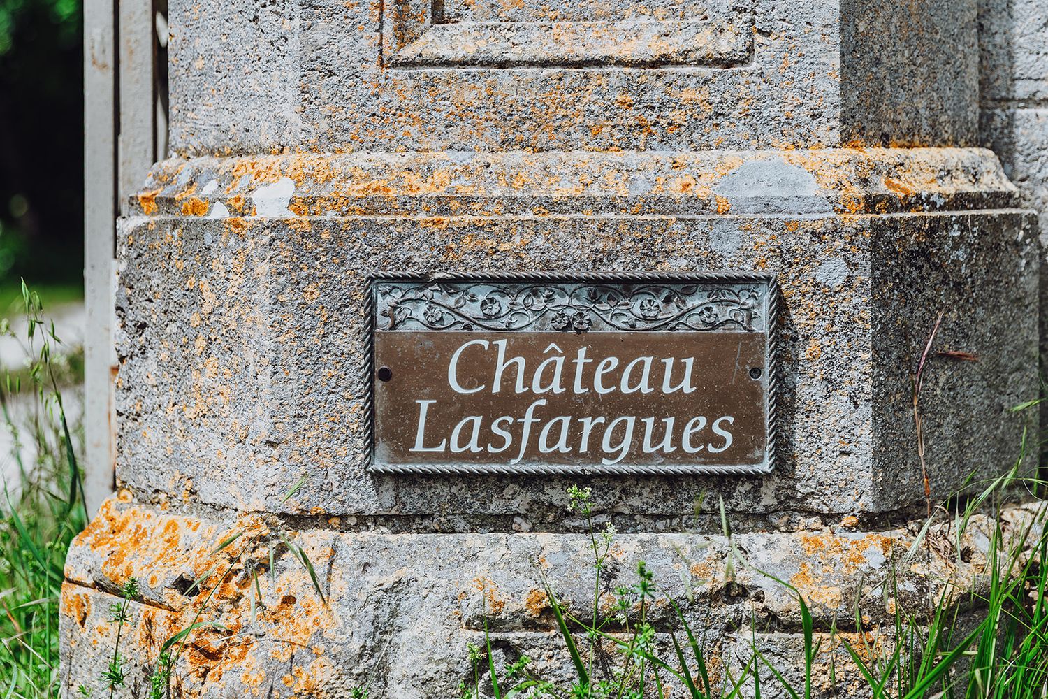 Stone pillars with rustic name plates for Chateau Lasfargues create an elegant entrance to a French estate.