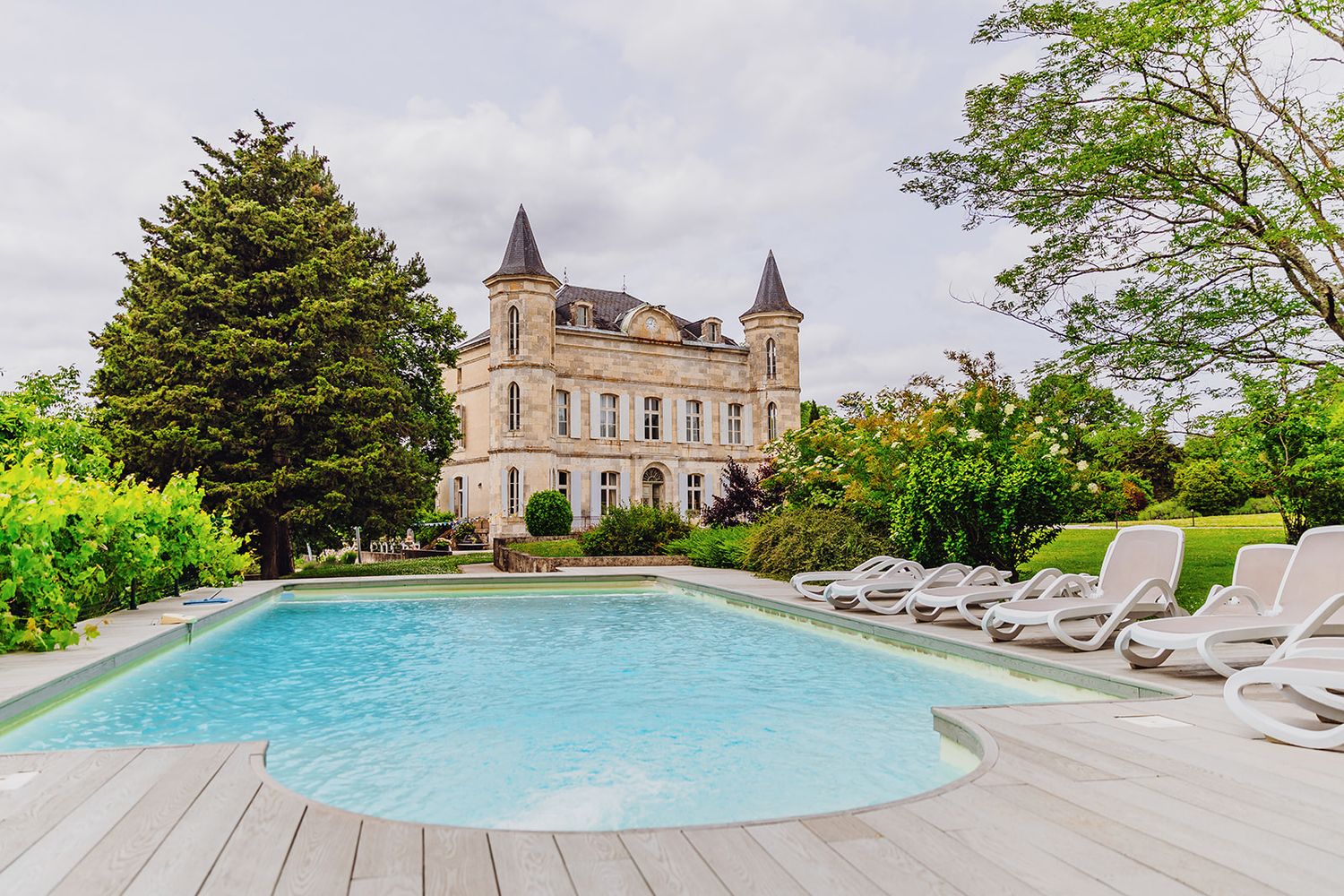 Panoramic view of a luxury chateau property with multiple swimming pools and manicured gardens.