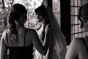 Black and white photo of groom tying laces on classic leather dress shoes before wedding ceremony.