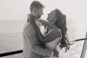 Black and white romantic portrait of bride and groom embracing on cruise ship deck over ocean.