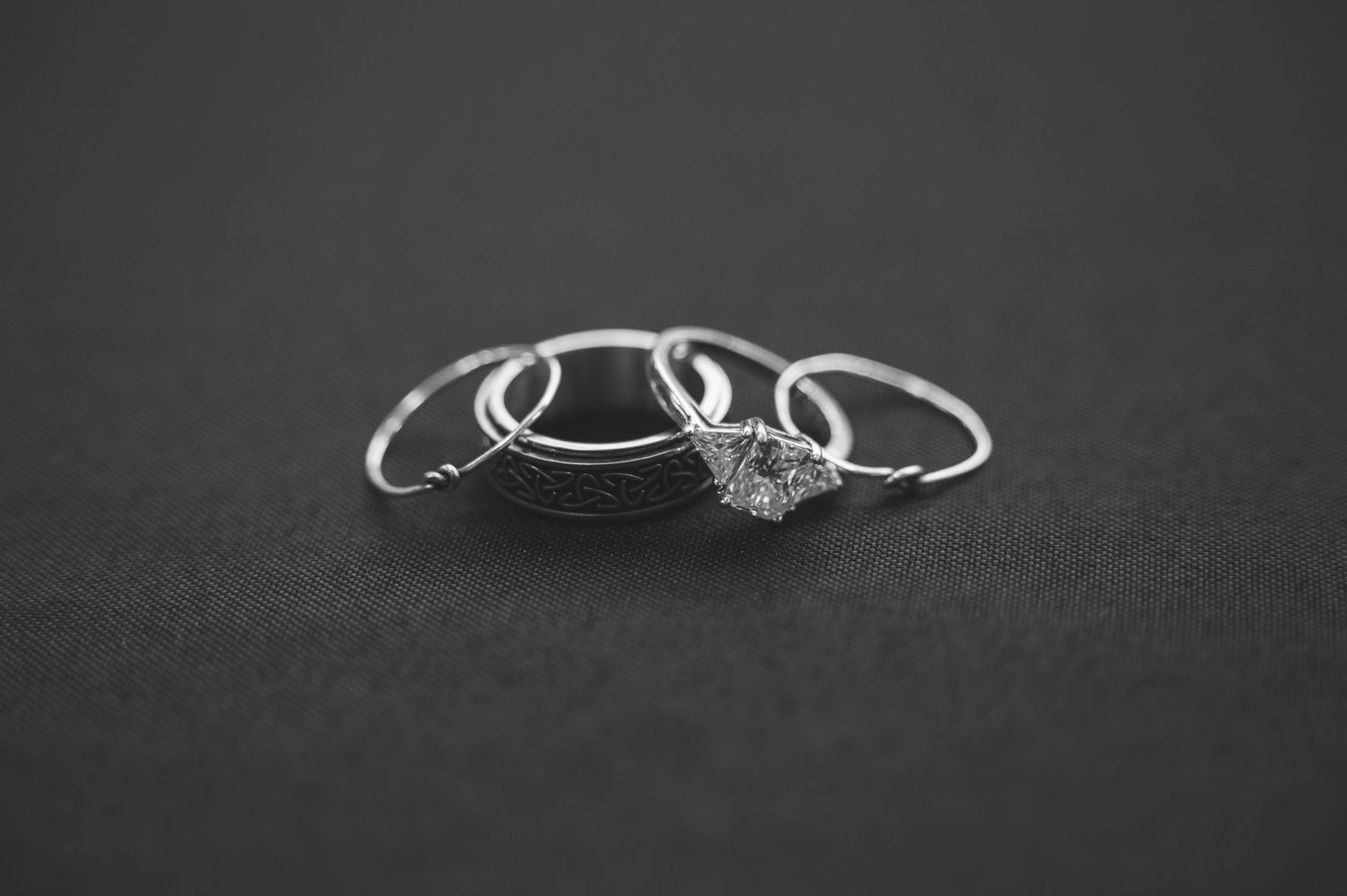 A delicate silver engagement ring with a sparkling diamond solitaire displayed on a dark gray background.