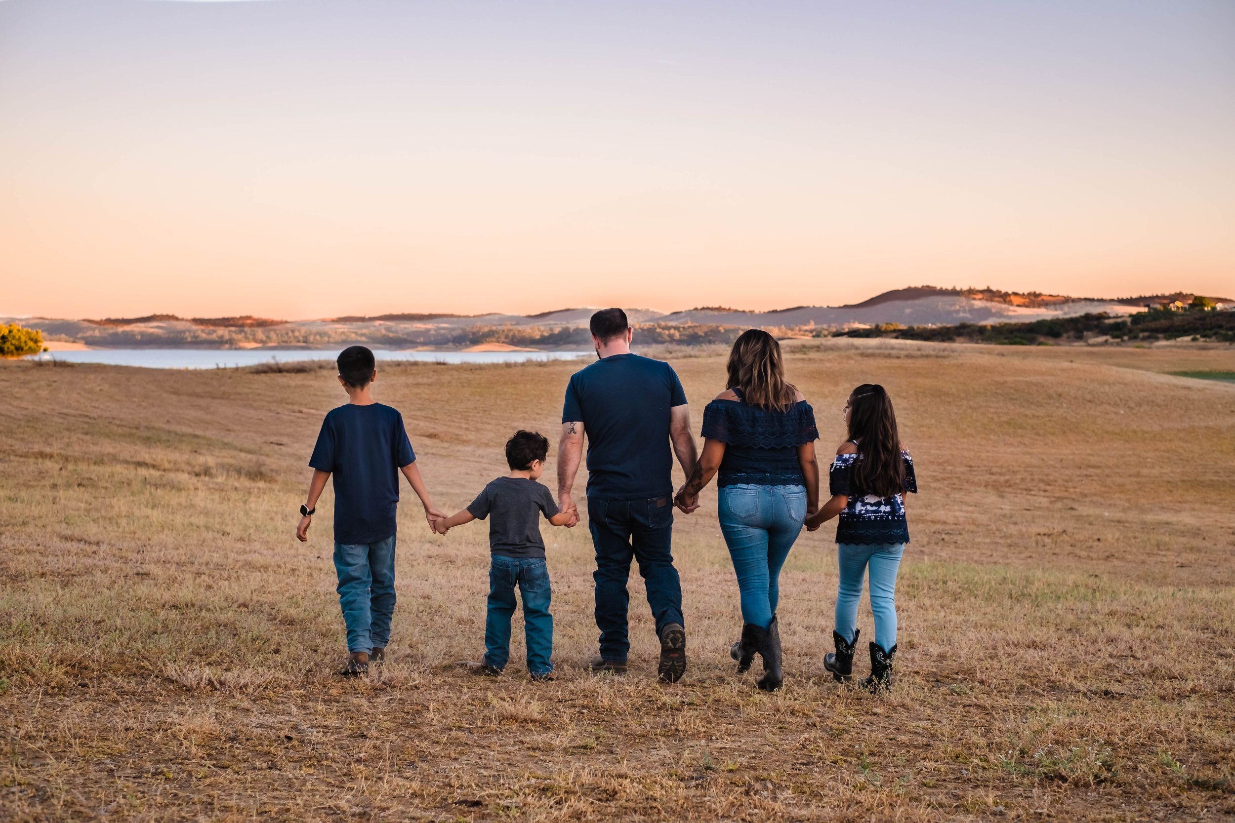 A group of people walking together across a lake hogan in valley springs ca at sunset with mountains in the distance.