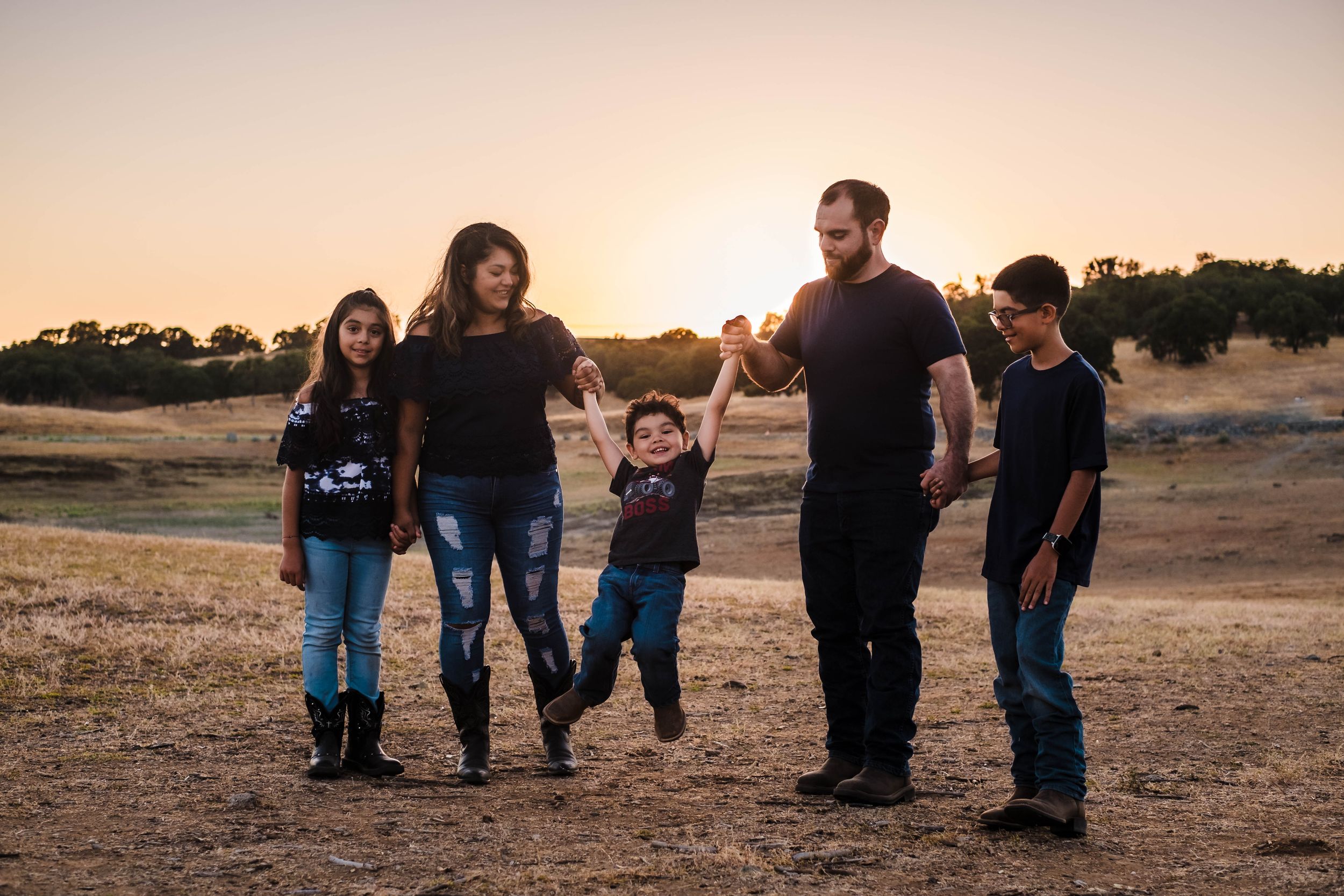 A group of people walking together in a line at sunset creating silhouettes against the golden sky. Lake hogan family photo session.