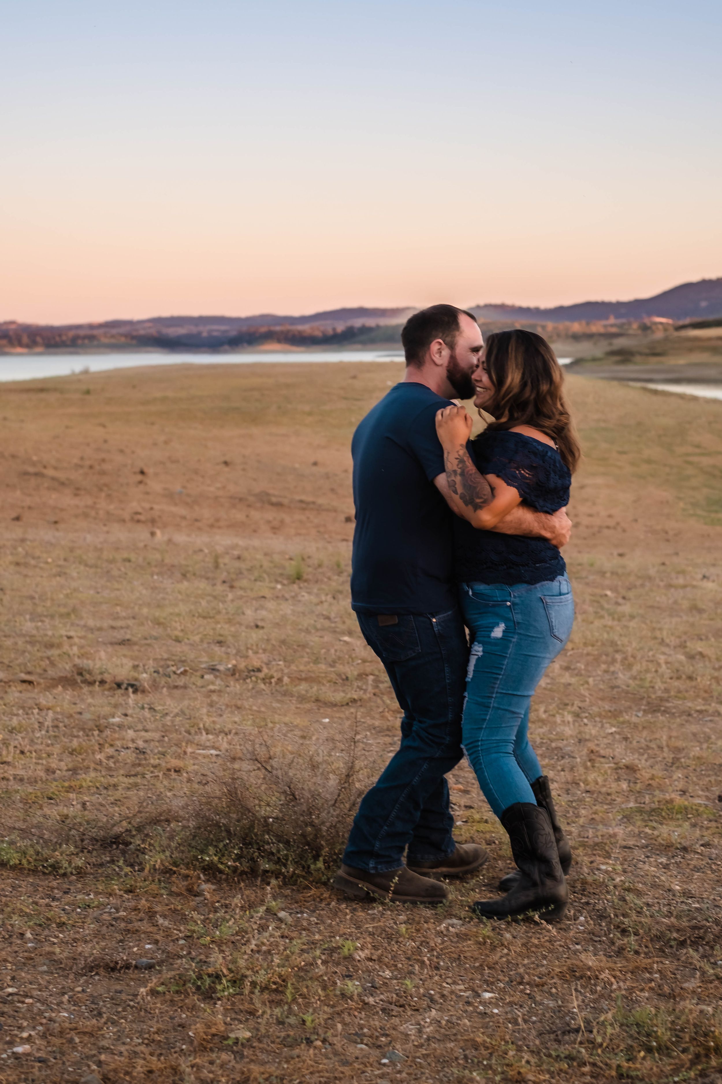 A couple embraces and dances together at sunset  stealing a few moments alone during their family photo session in valley springs.