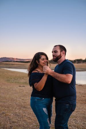 Couple in matching denim and navy outfits share tender moments during sunset photoshoot on the shore of lake hogan in valley springs ca
