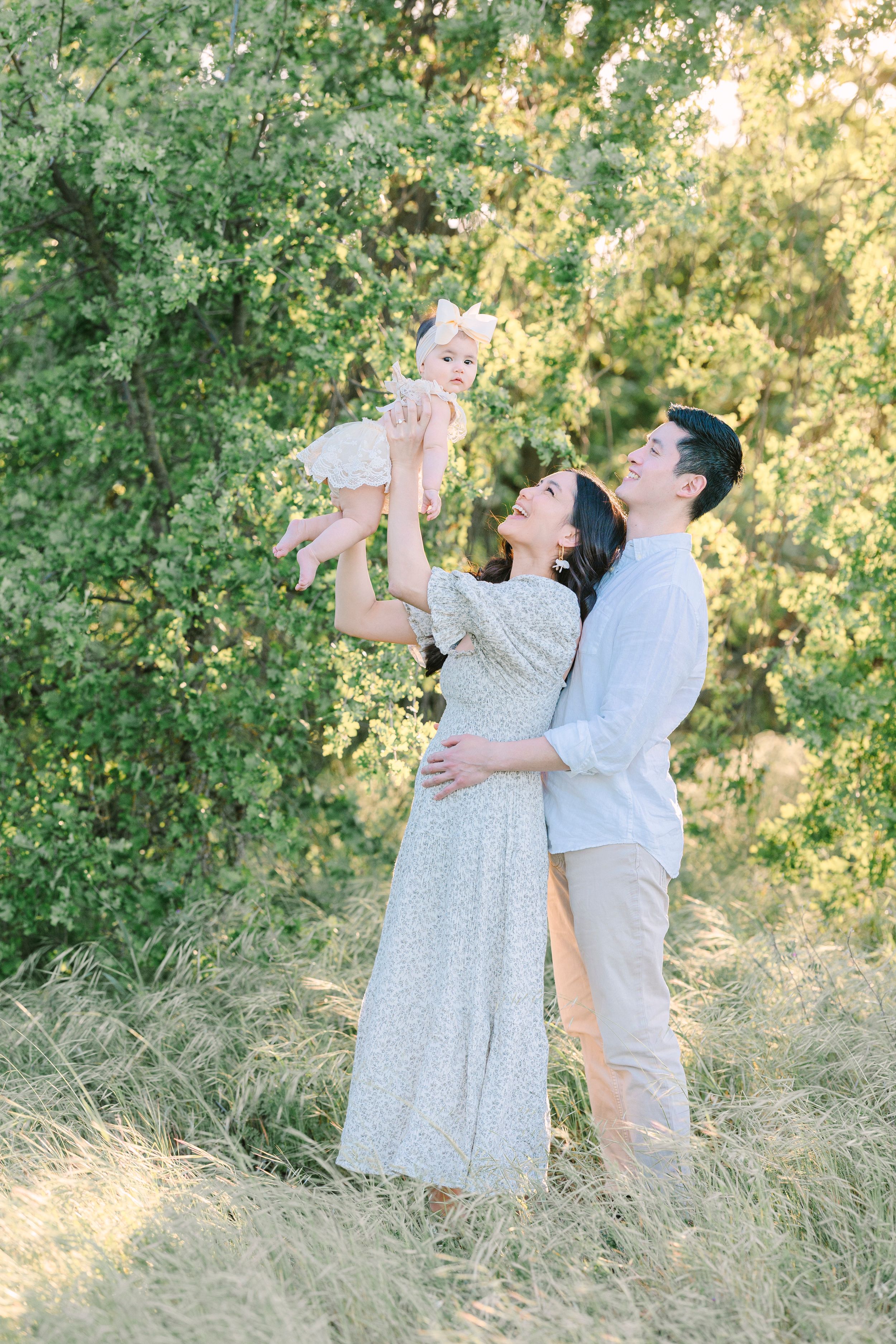 A family shares joyful moments together in a field with golden sunlight filtering through trees.