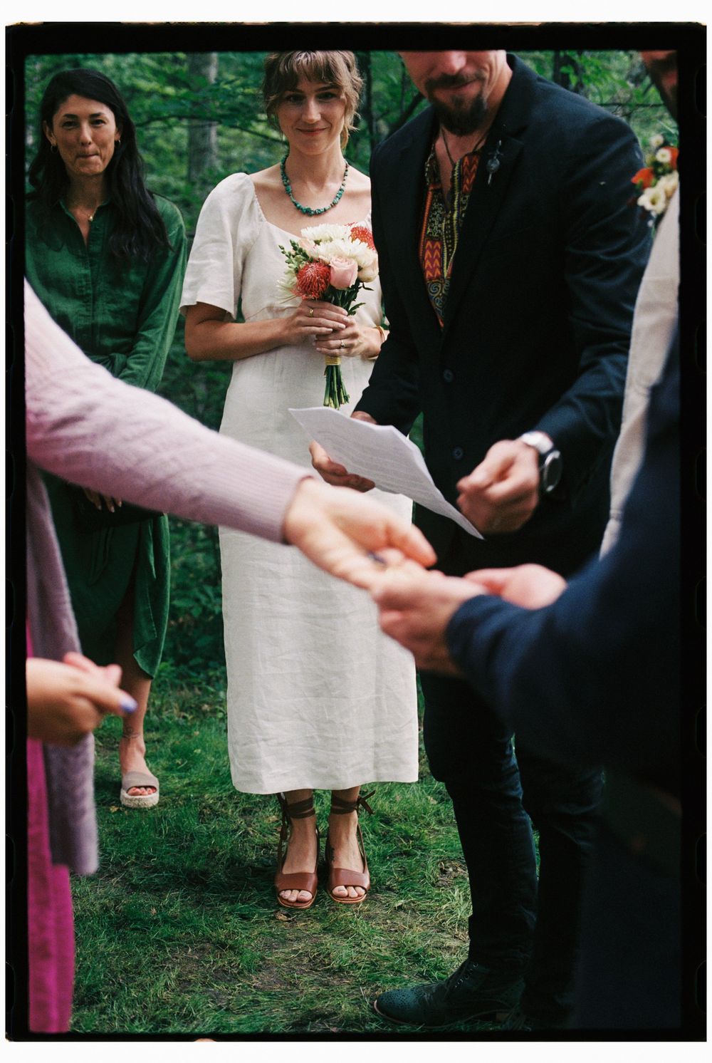 The sister and ring bearer hands off the ring to brother of the groom during intimate wedding ceremony in the forest in upstate New York.