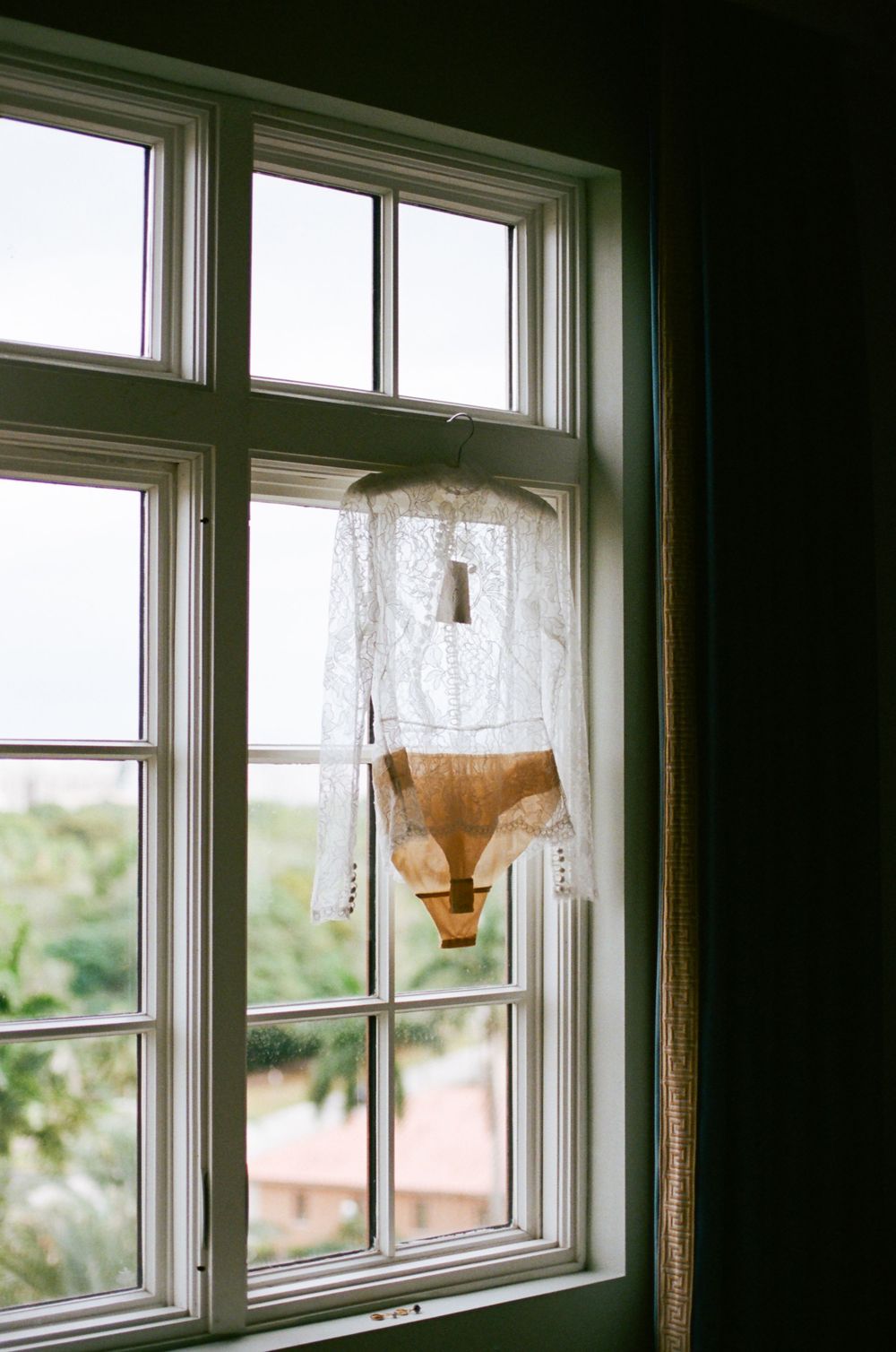 Three identical windows with lace curtains and pendant lights in a dark room with natural lighting.