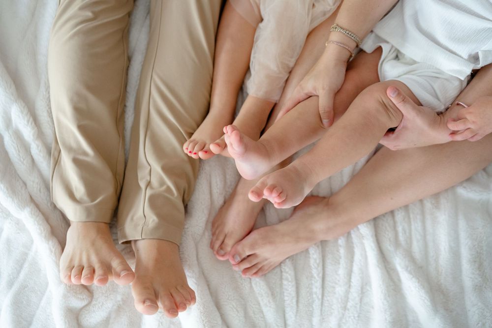 Bare feet of people lying together on white bedding showing closeness and intimacy.