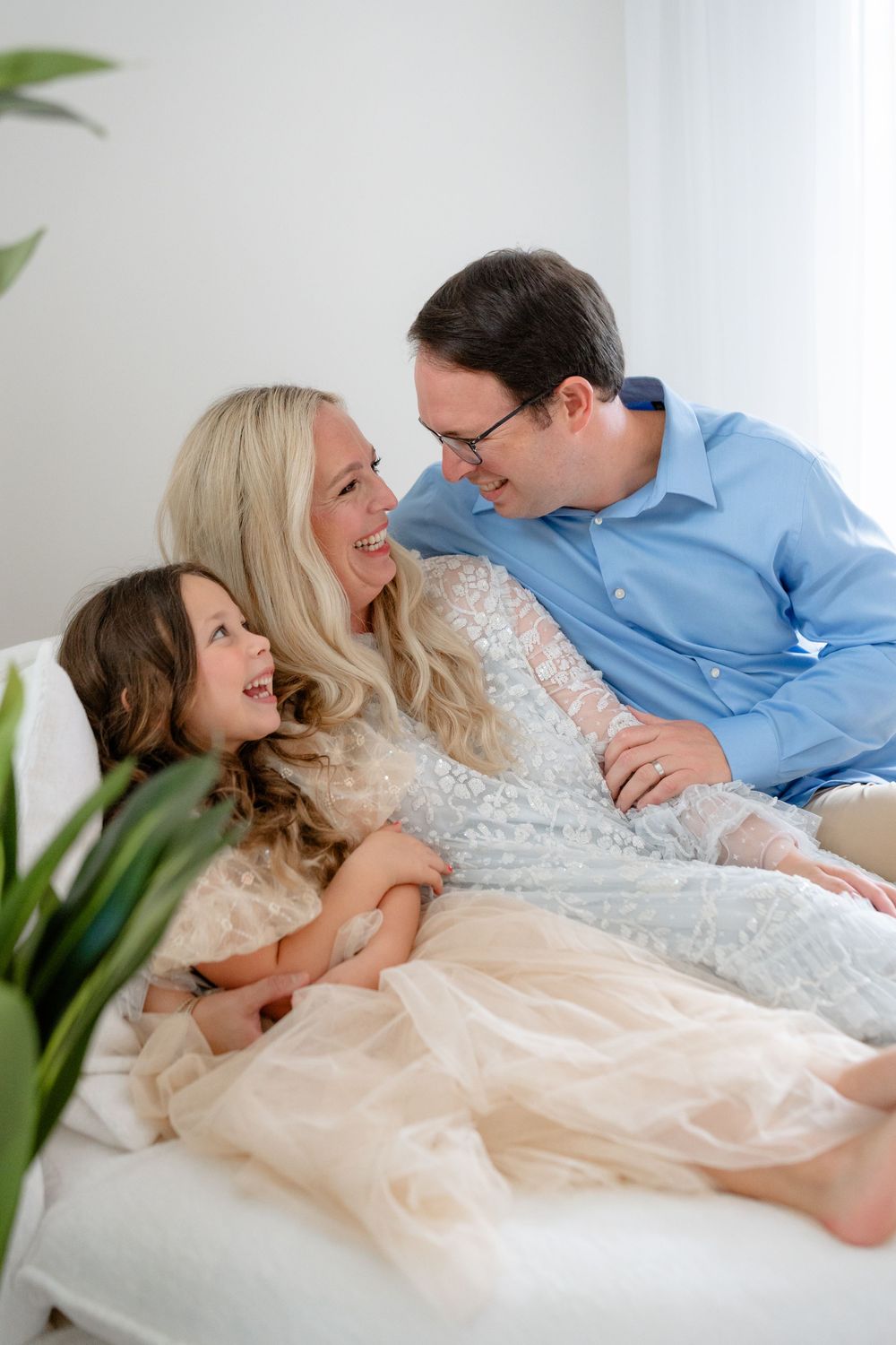 A joyful family sharing laughter while relaxing together on a white couch.