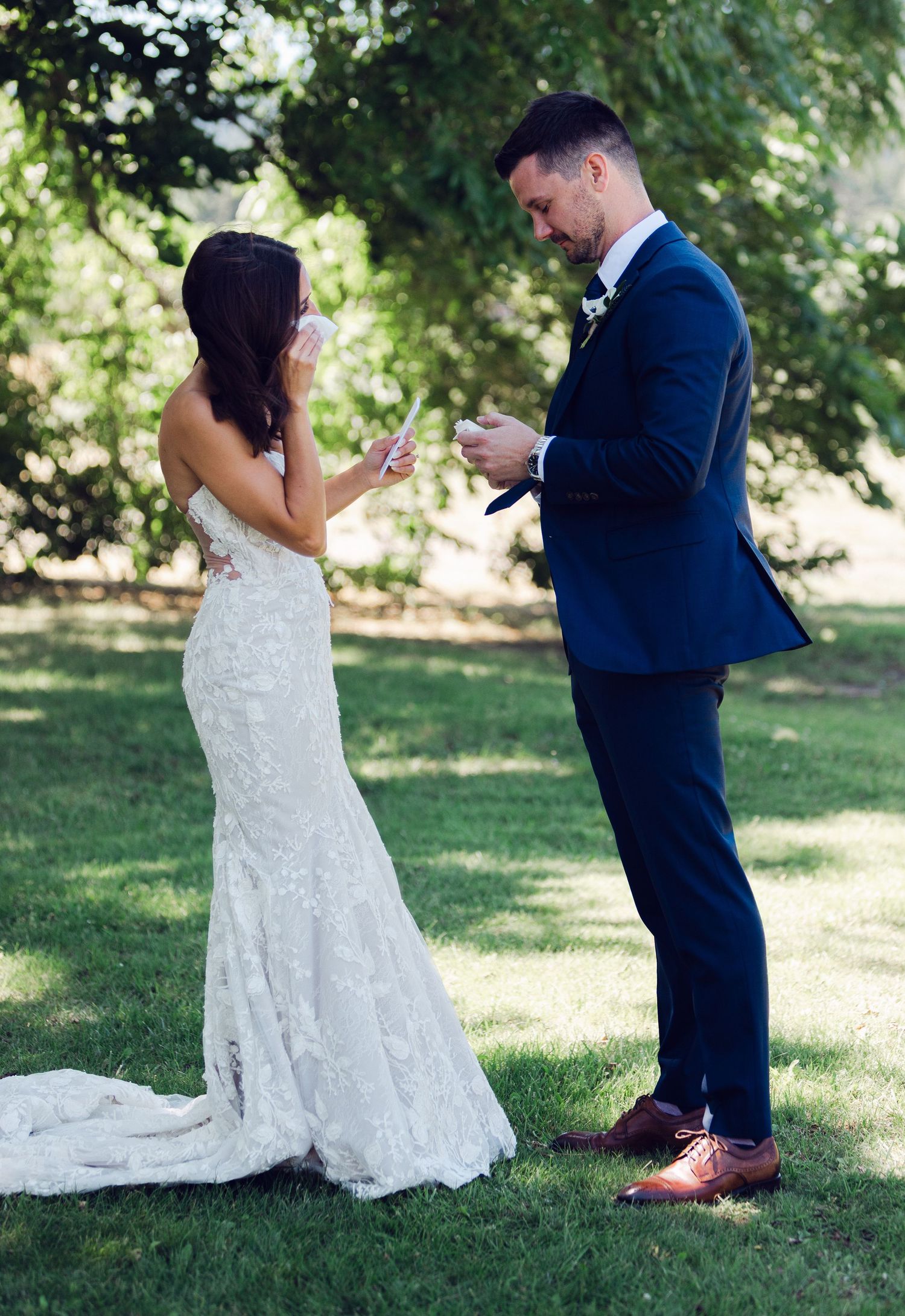 A couple shares a tender moment during their first look wedding photos in a sunlit garden setting.