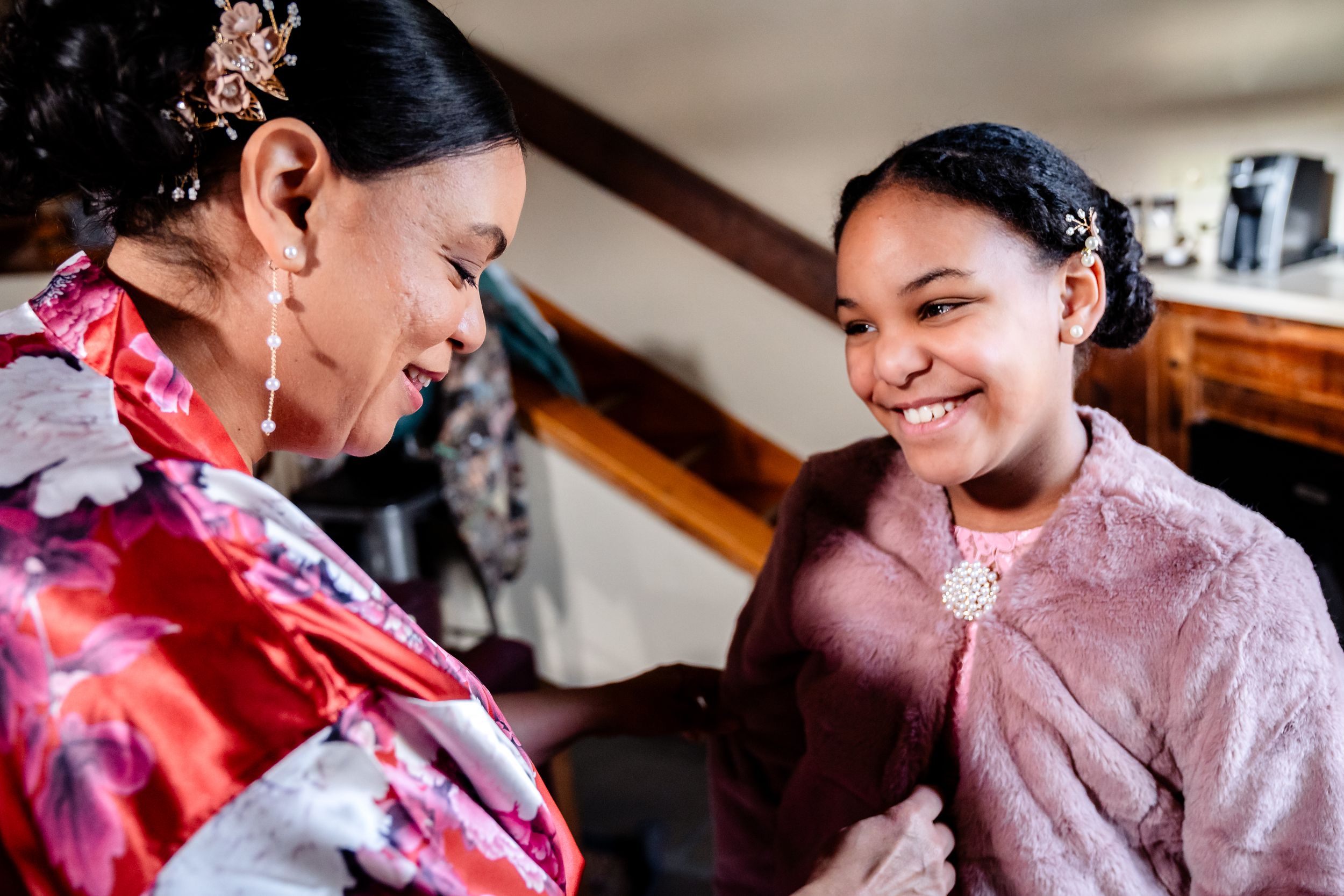 Bridesmaids in floral robes share joyful moments while preparing for a wedding celebration.