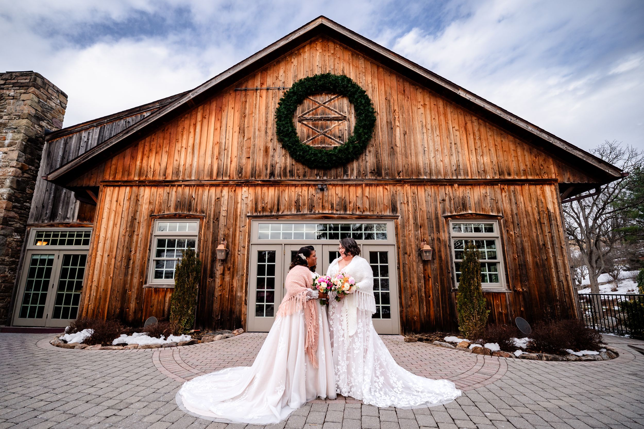 Rustic wooden barn venue decorated for a wedding with elegant gowns and romantic lighting at dusk.