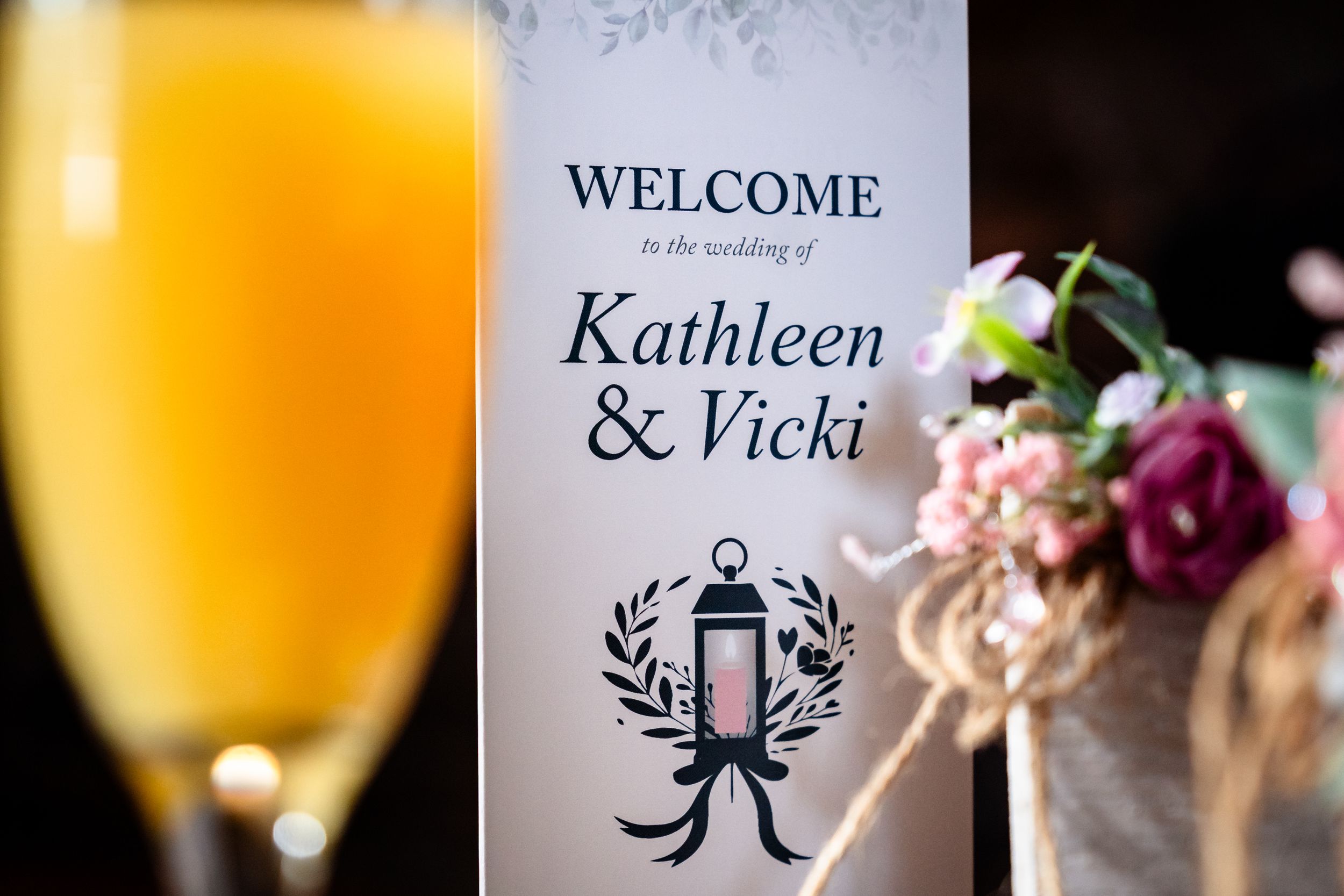 Wedding welcome sign with elegant calligraphy displayed next to mimosa cocktail.