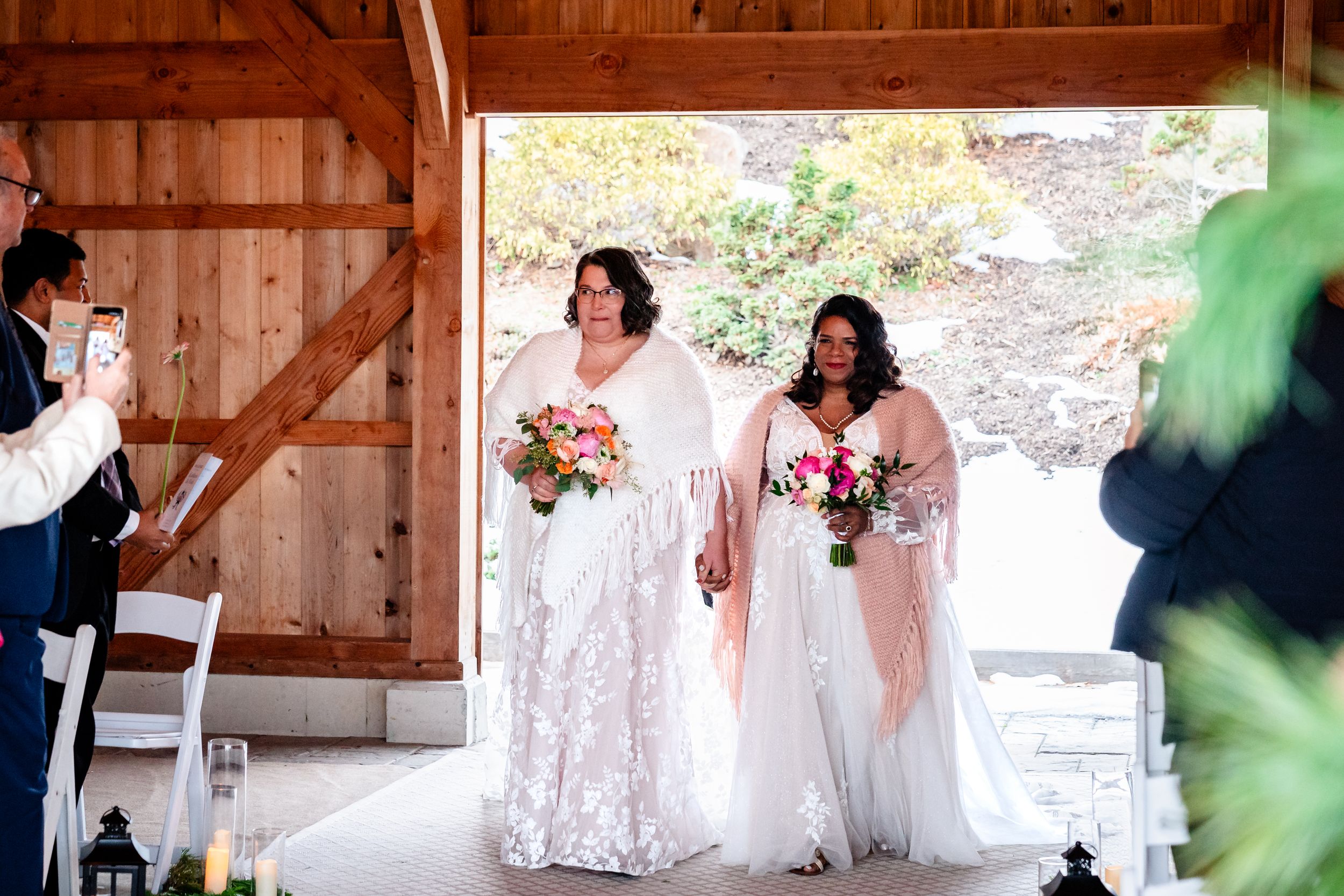 Wedding celebration inside a rustic wooden barn with natural light streaming through windows.
