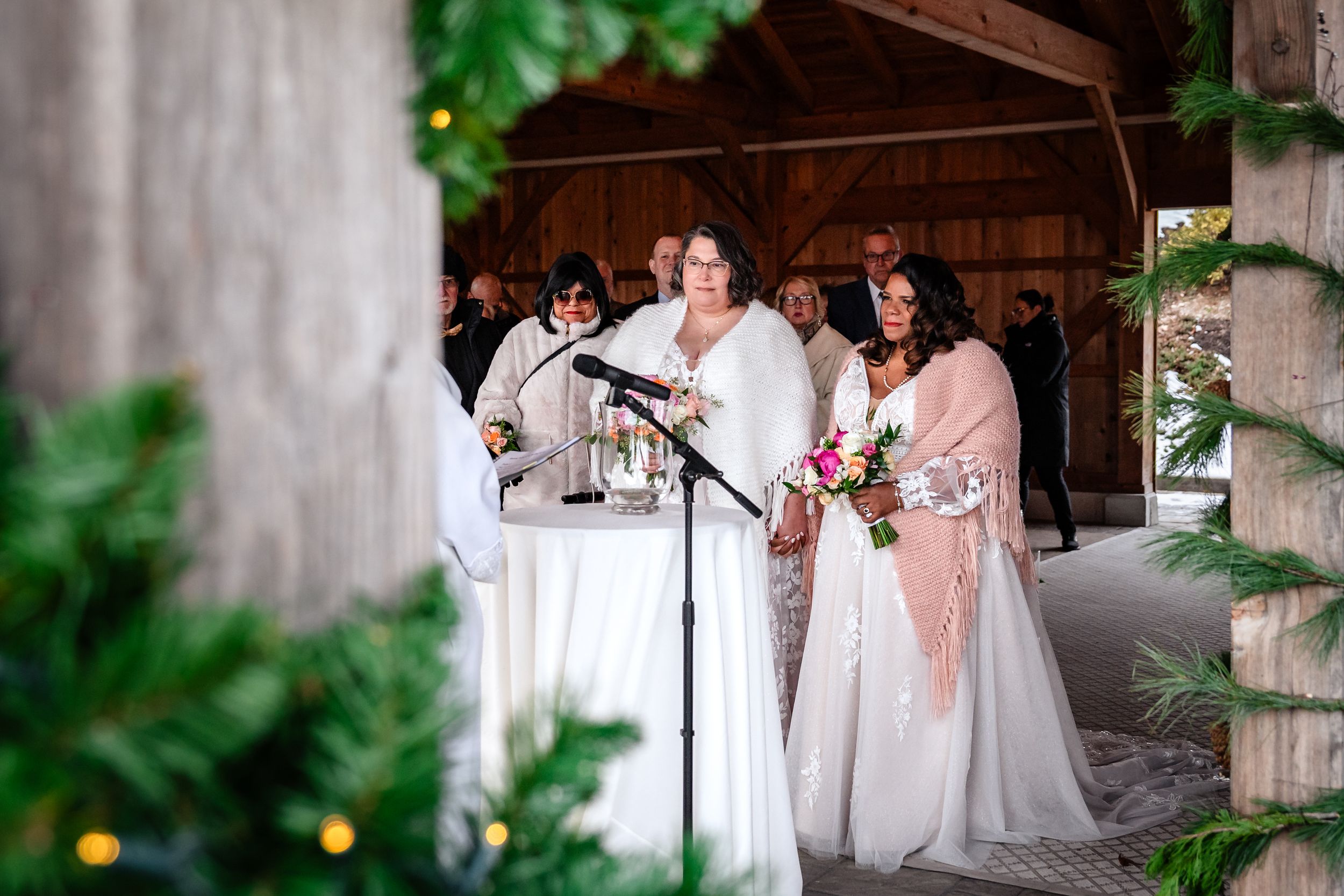 Wedding party celebrates inside rustic barn venue decorated with greenery and natural light.