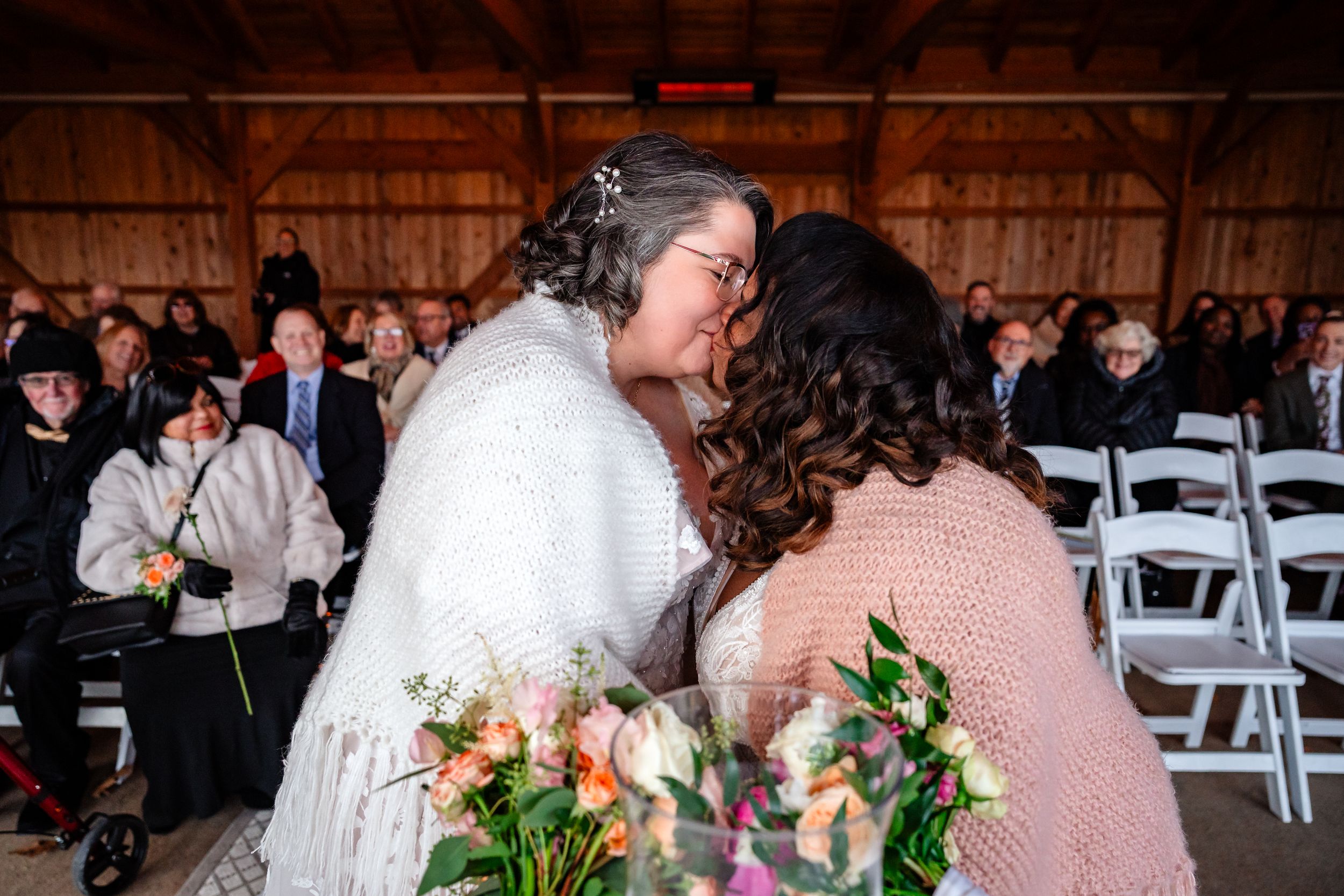 Couple dancing together during their first dance at a rustic barn wedding reception with guests watching.