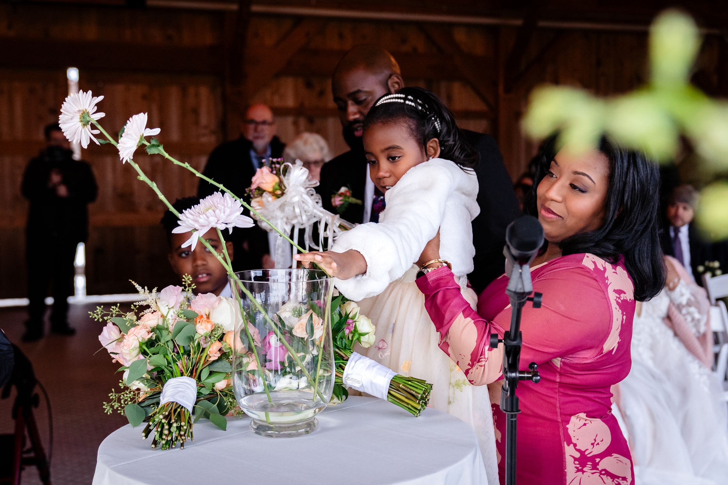 Wedding party enjoys intimate conversation at decorated reception table with floral centerpieces.