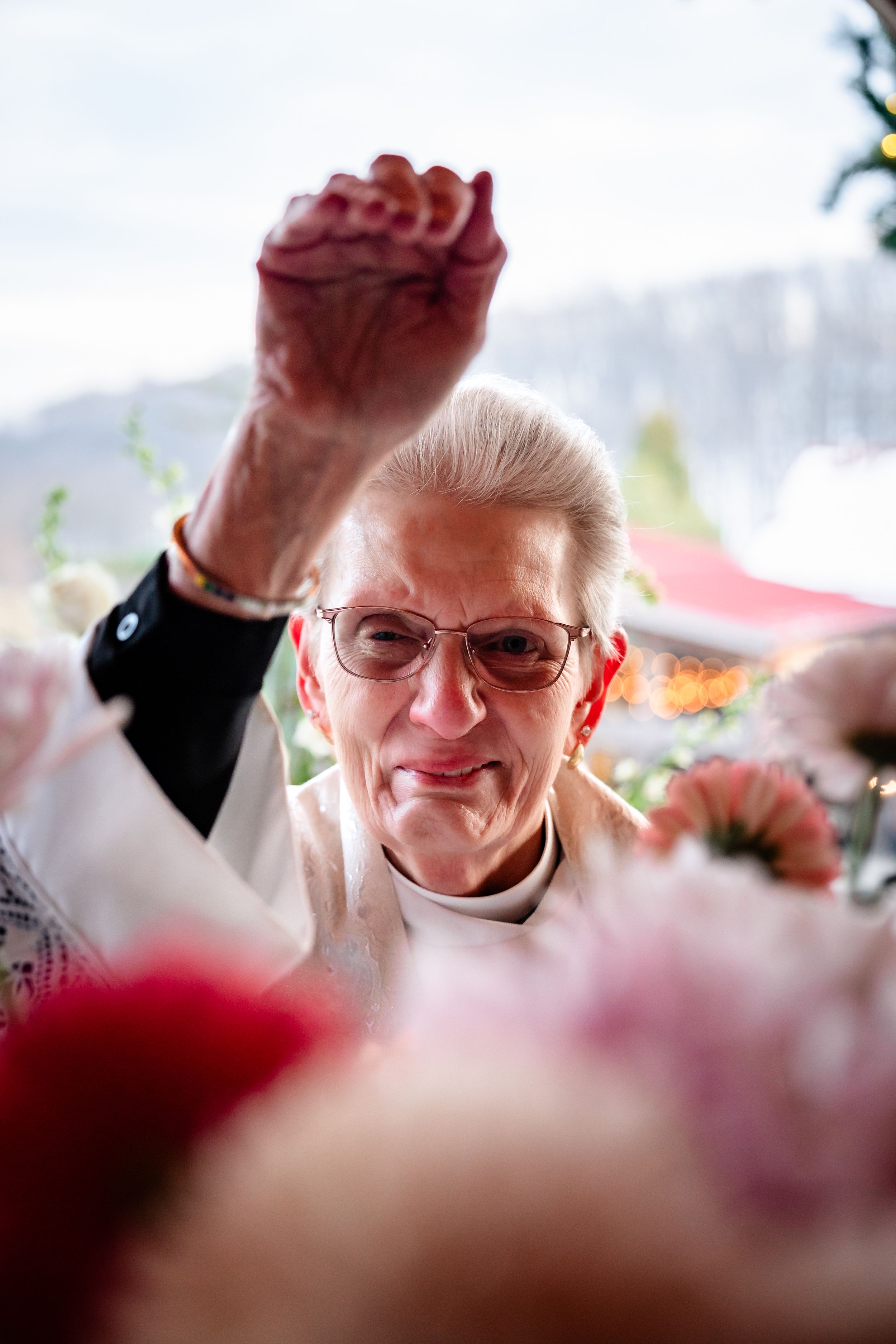A person wearing glasses raises their fist in celebration during a festive event.