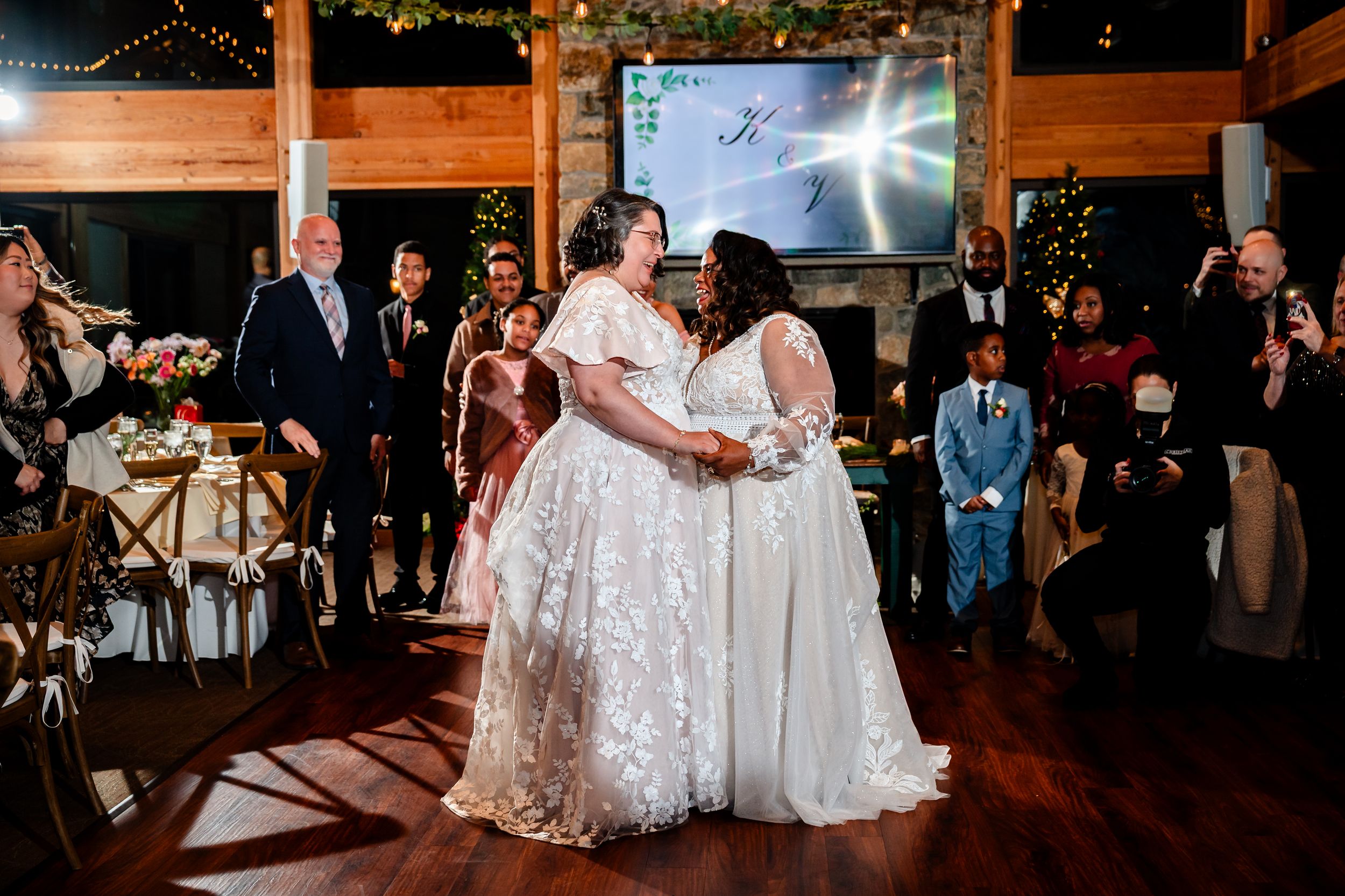 Guests gather to watch a couple share their first dance together at an elegant indoor wedding reception.