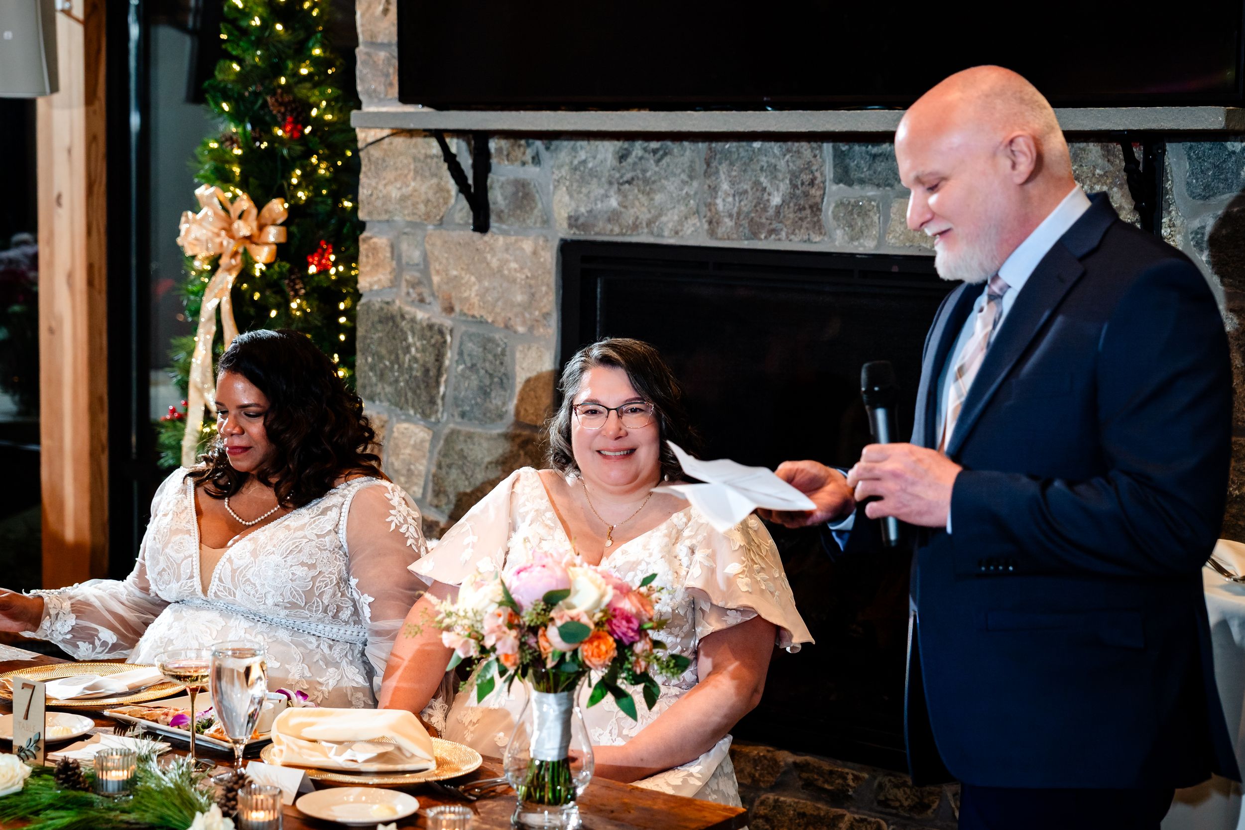 Wedding guests enjoying dinner at long tables in an elegantly decorated rustic venue.