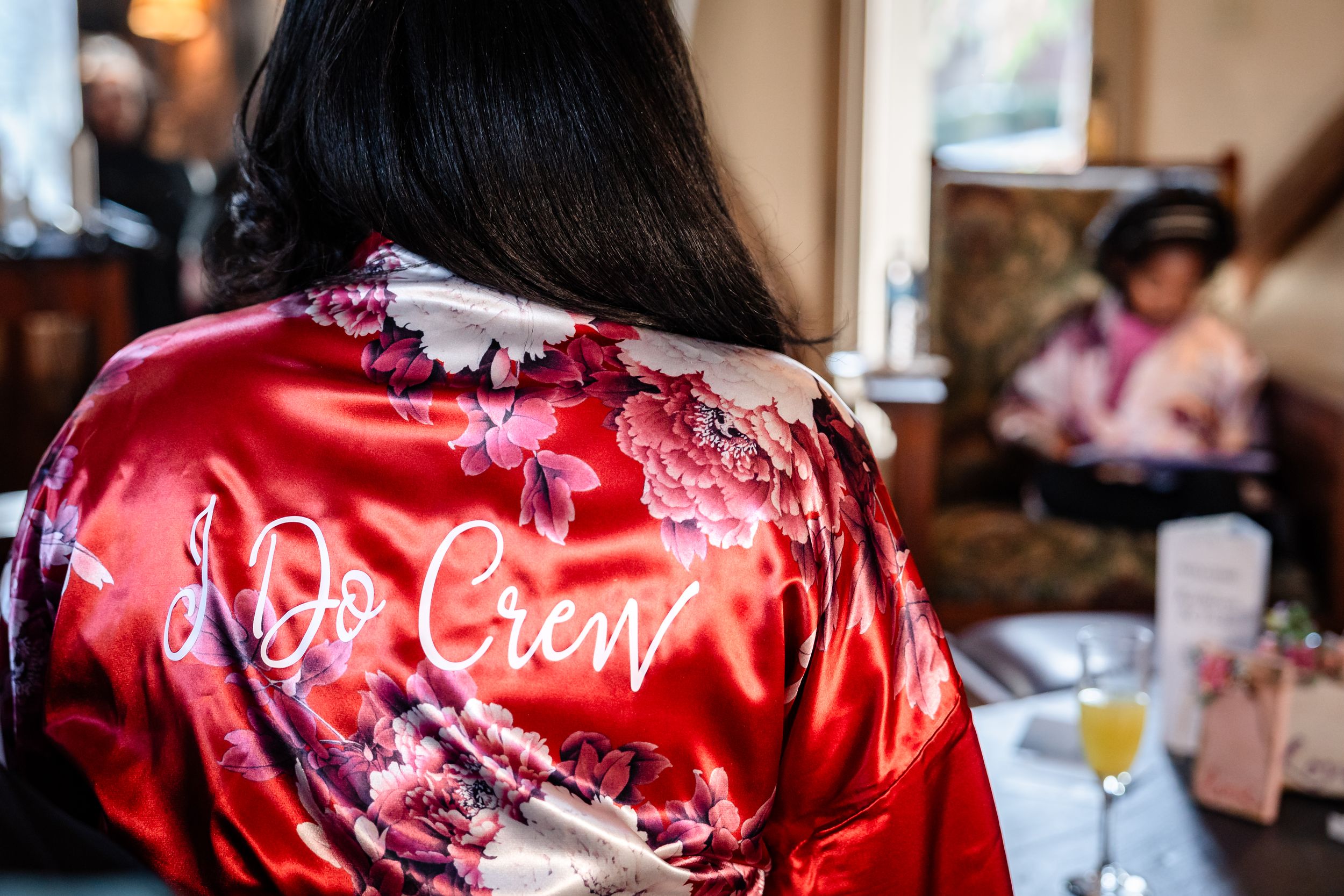 Red satin robes with custom text hang on display for wedding party preparation.