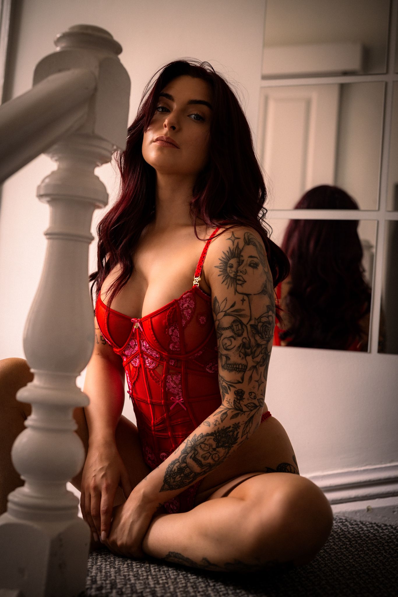 A series of moody boudoir photos featuring a person in red lingerie with tattoos against a light interior background.