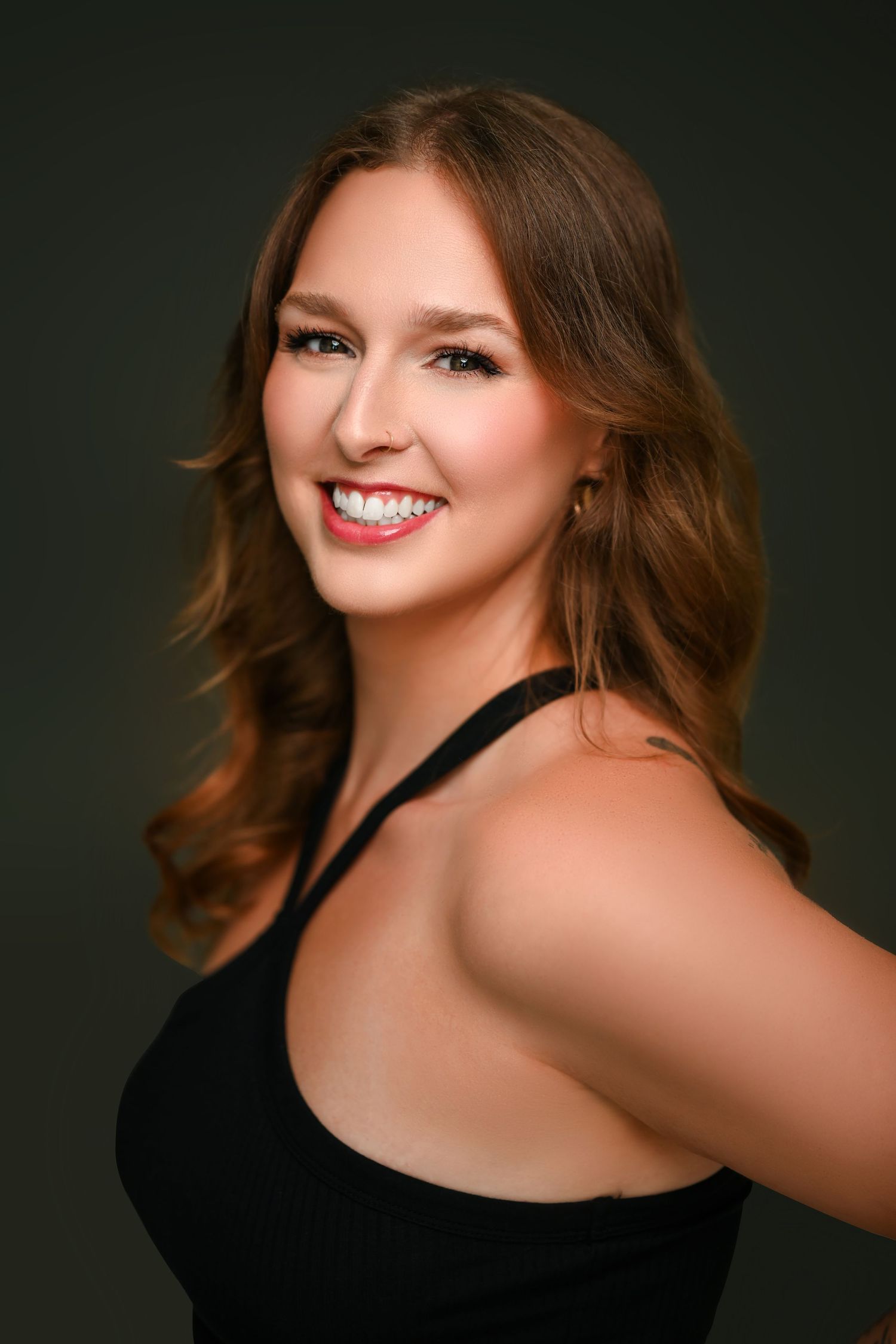 Studio portrait with dramatic lighting featuring person in black attire against dark background.